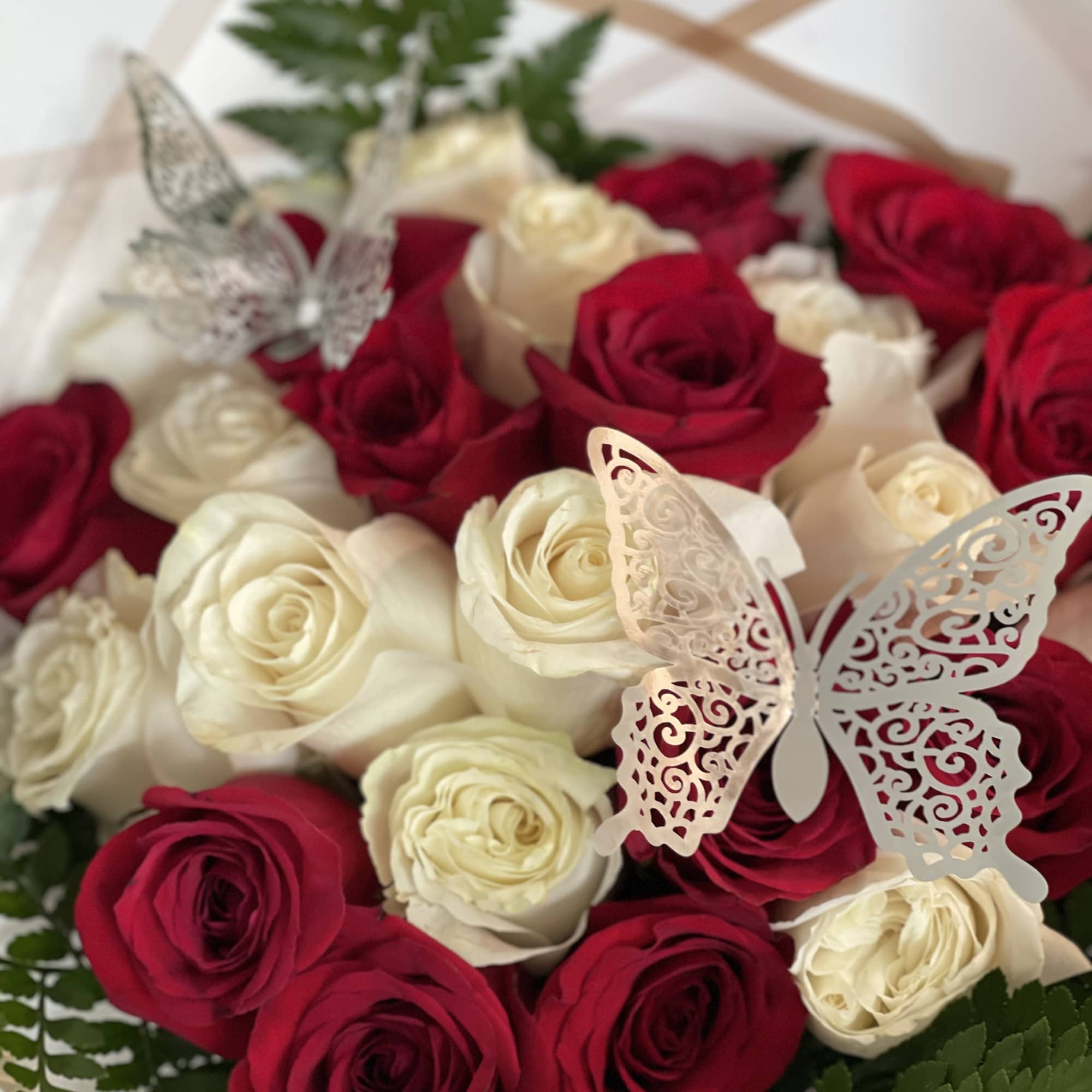 Bouquet of red and white roses with decorative butterfly accents