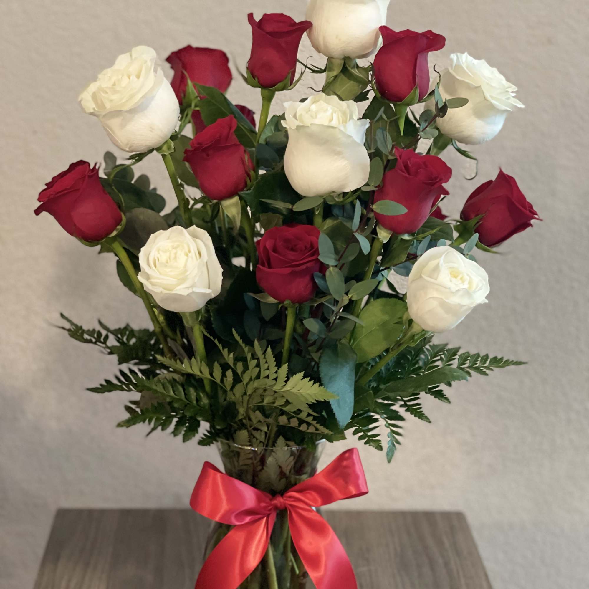 Bouquet of red and white roses in a glass vase with a red ribbon