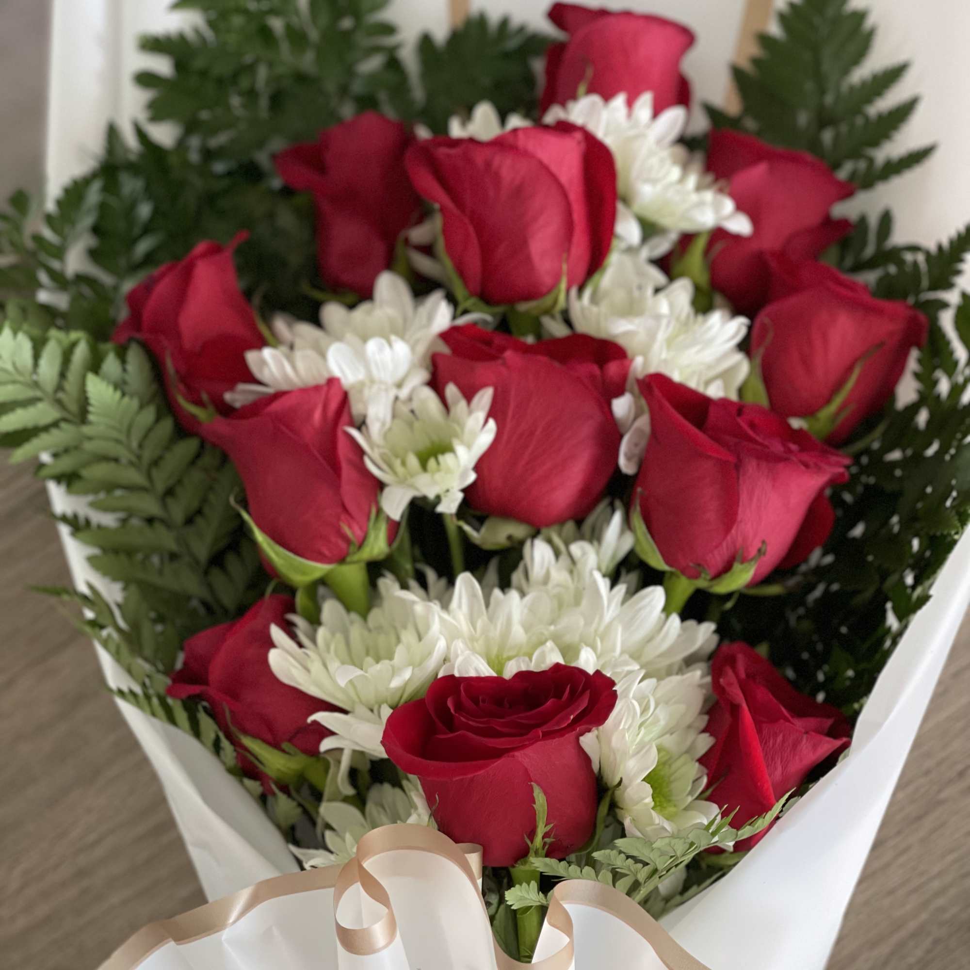 Bouquet of red roses and white daisies wrapped in white paper