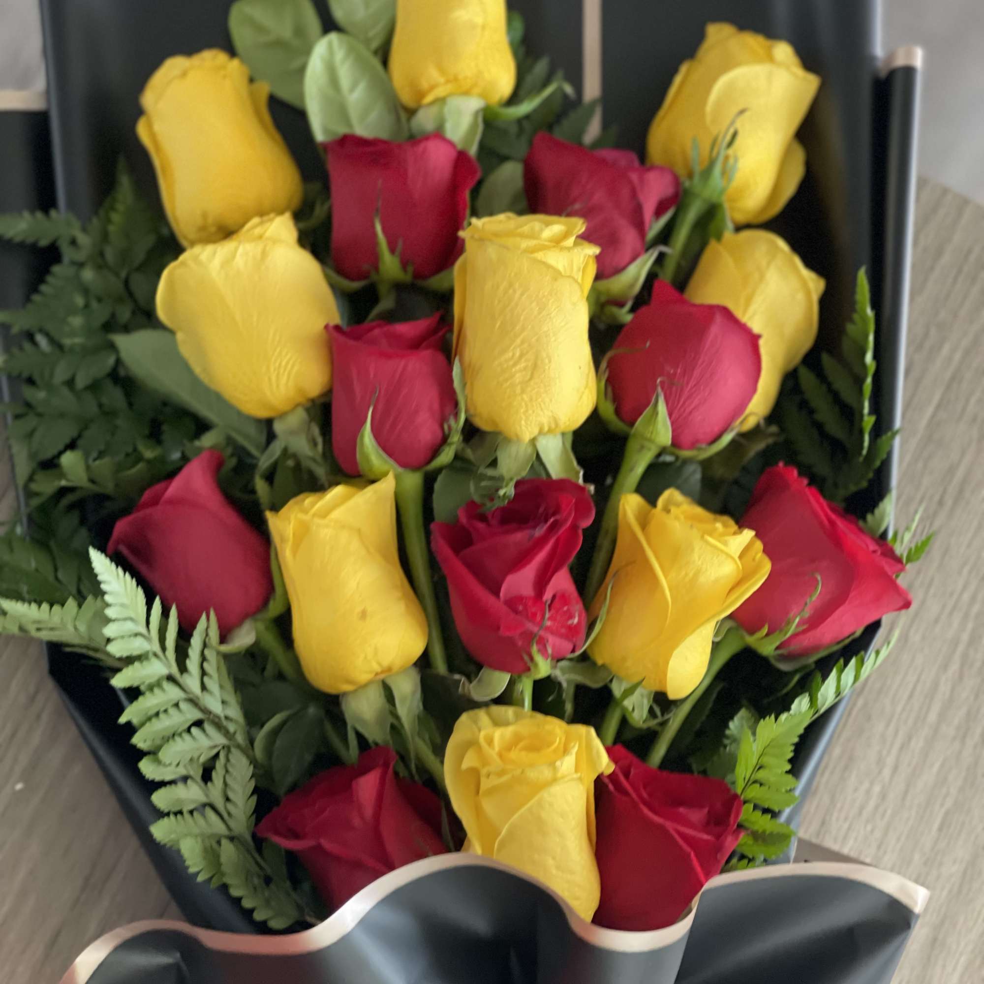 Bouquet of red and yellow roses wrapped in black paper