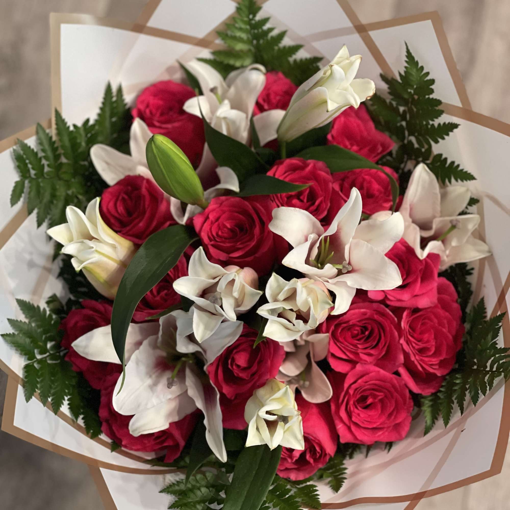 Bouquet of hot pink roses and white lilies wrapped in paper