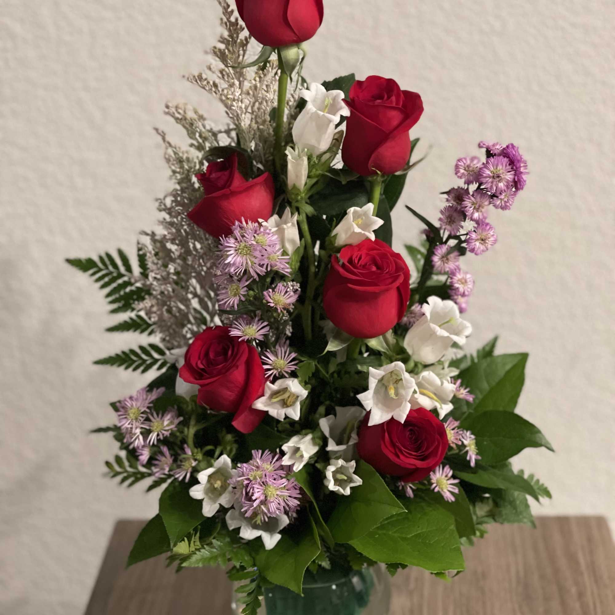 Red roses and white bellflowers in a clear glass vase