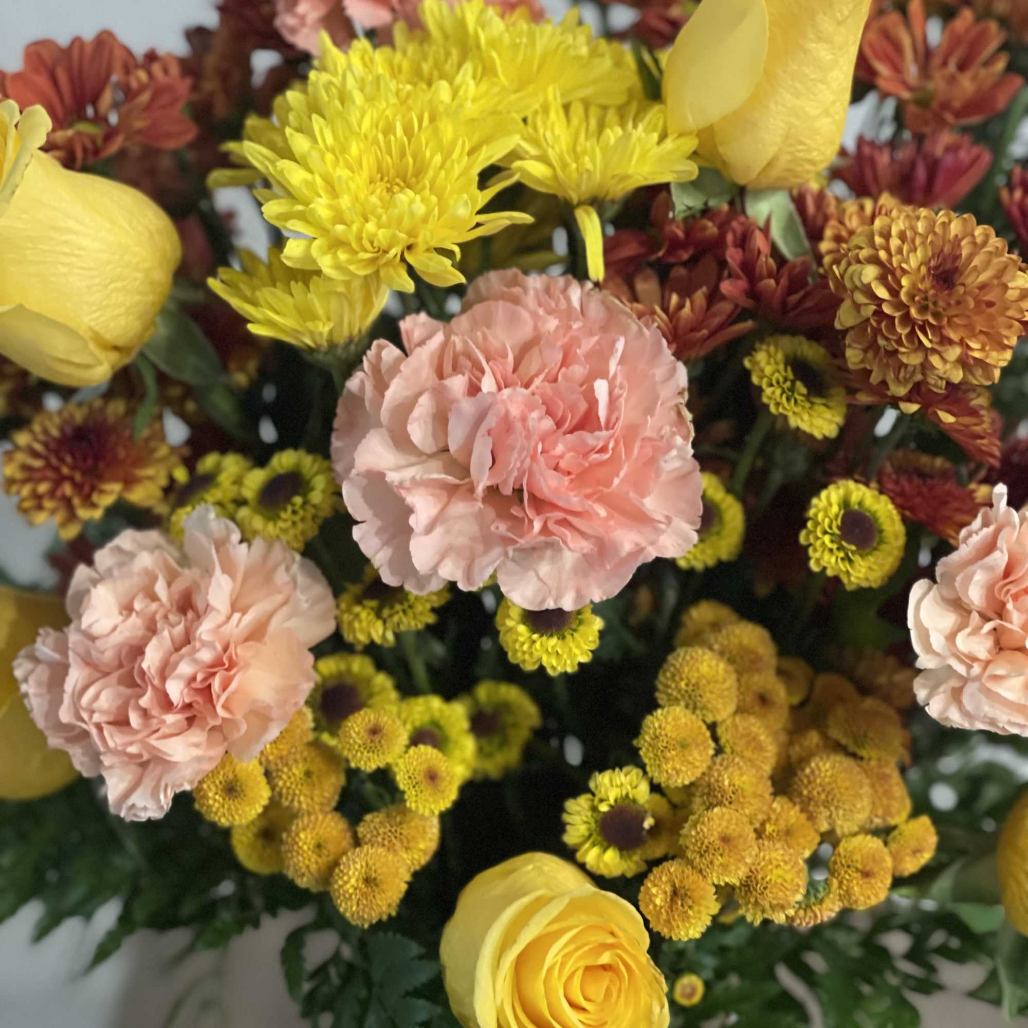 Bouquet of yellow roses, pink carnations, and chrysanthemums
