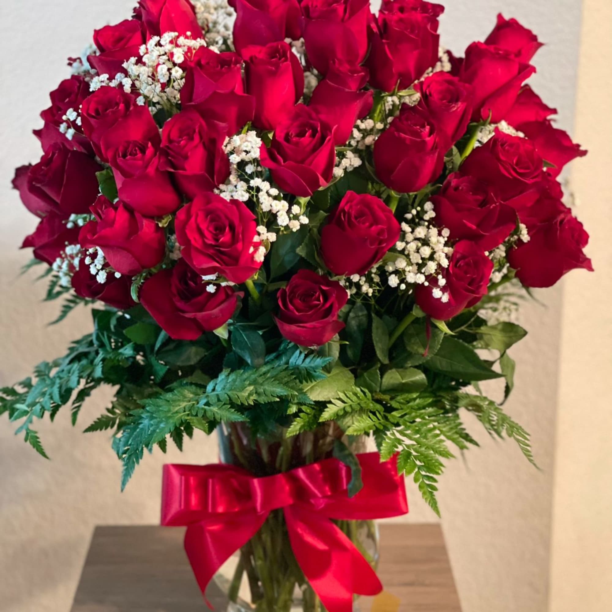 Bouquet of red roses in a glass vase with a red ribbon