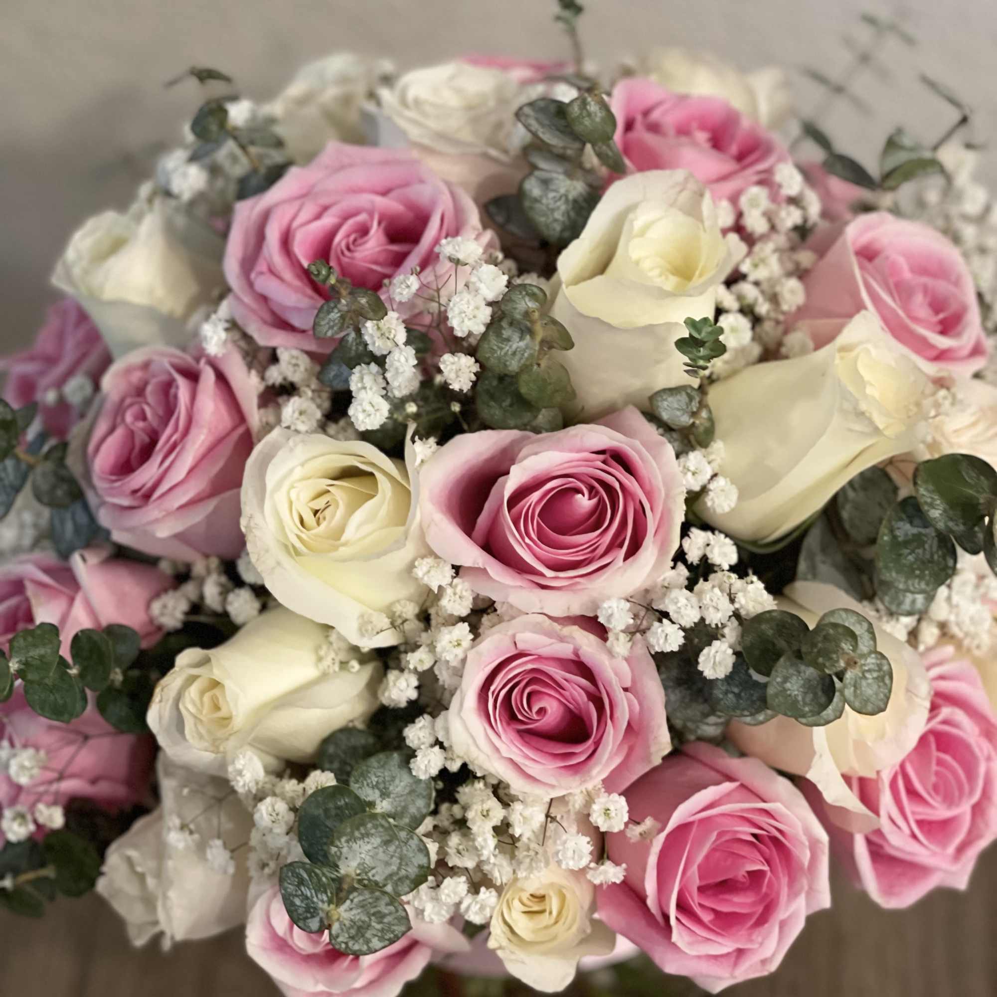 Pink and white roses arranged with baby's breath in a vase