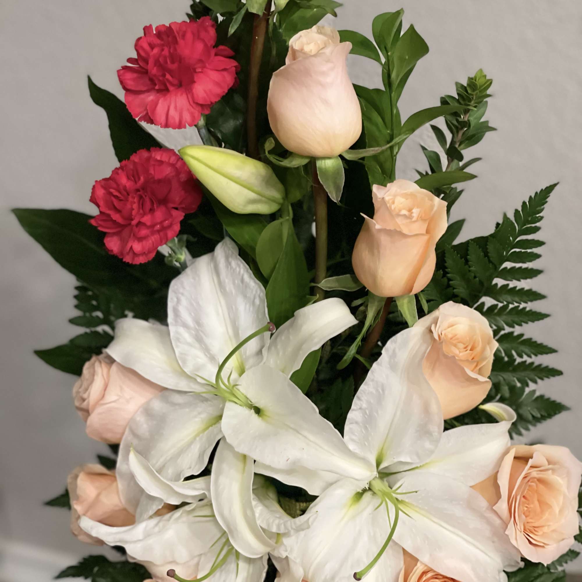 Bouquet of white lilies, peach roses, and red carnations