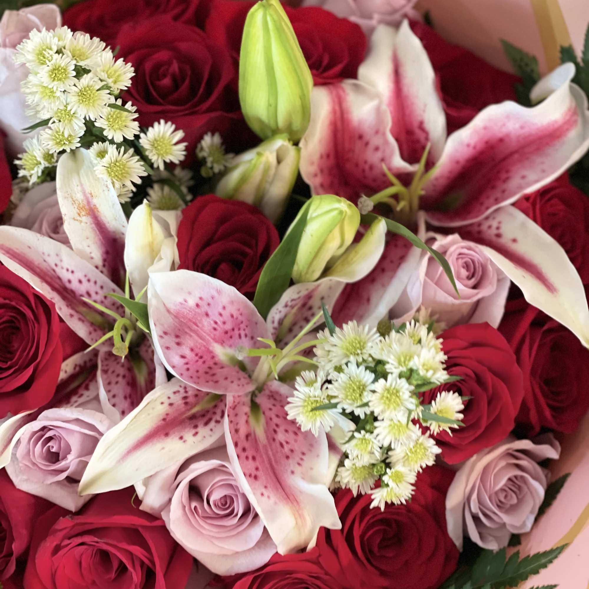 Bouquet of red and pink roses with pink lilies and white filler flowers