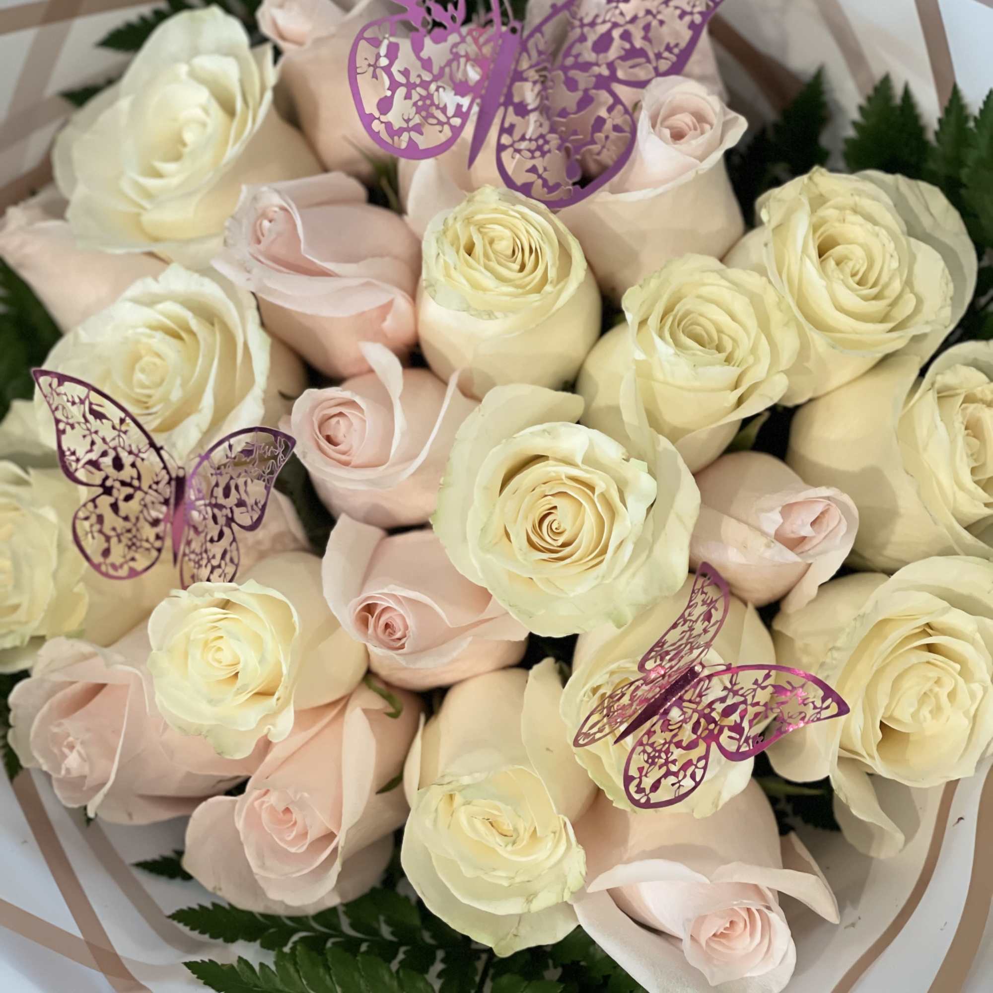 Bouquet of cream and blush roses with purple butterfly picks