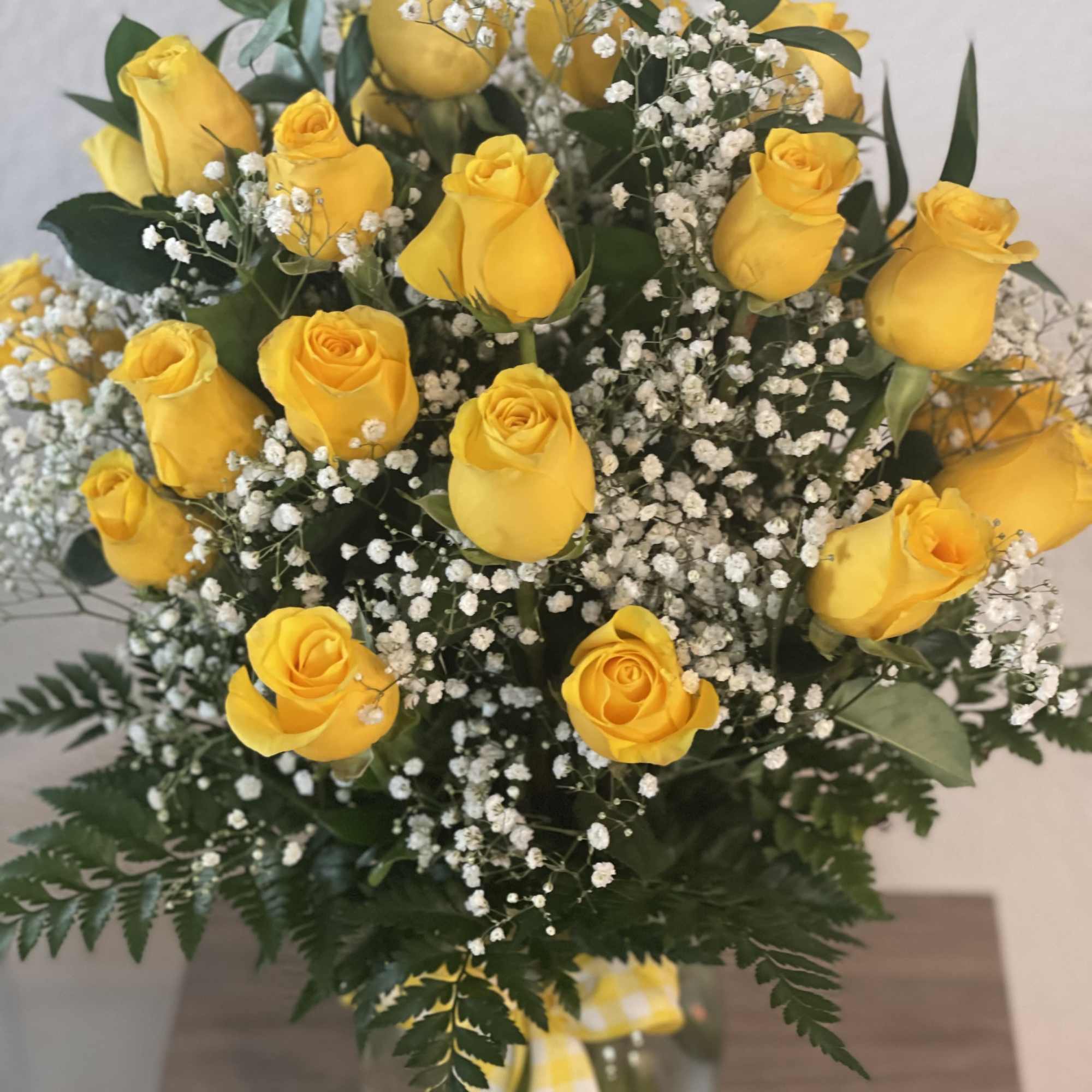 Yellow roses arranged with white baby's breath in a glass vase