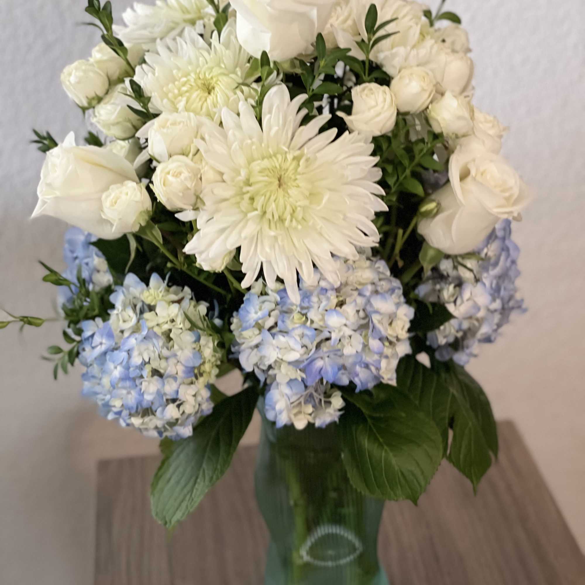 White and pale blue flowers arranged in a glass vase