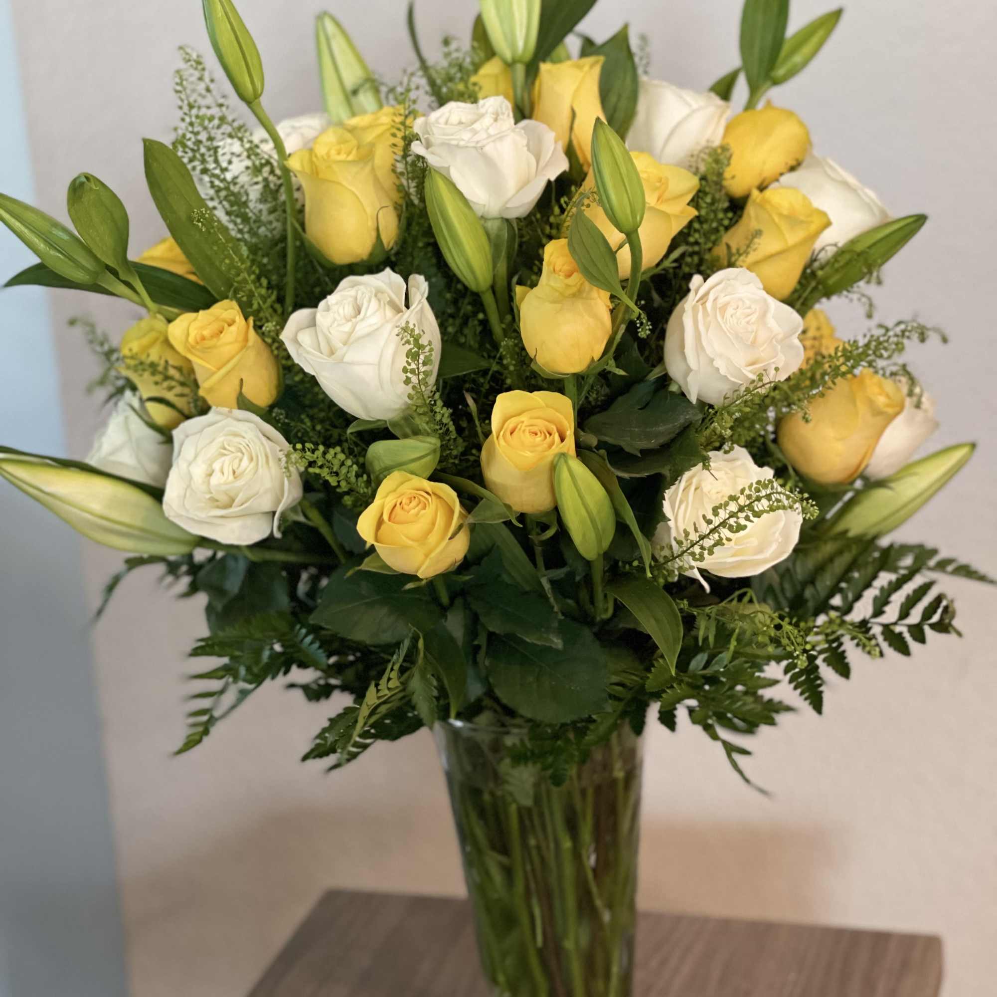 Yellow and white roses arranged in a tall glass vase