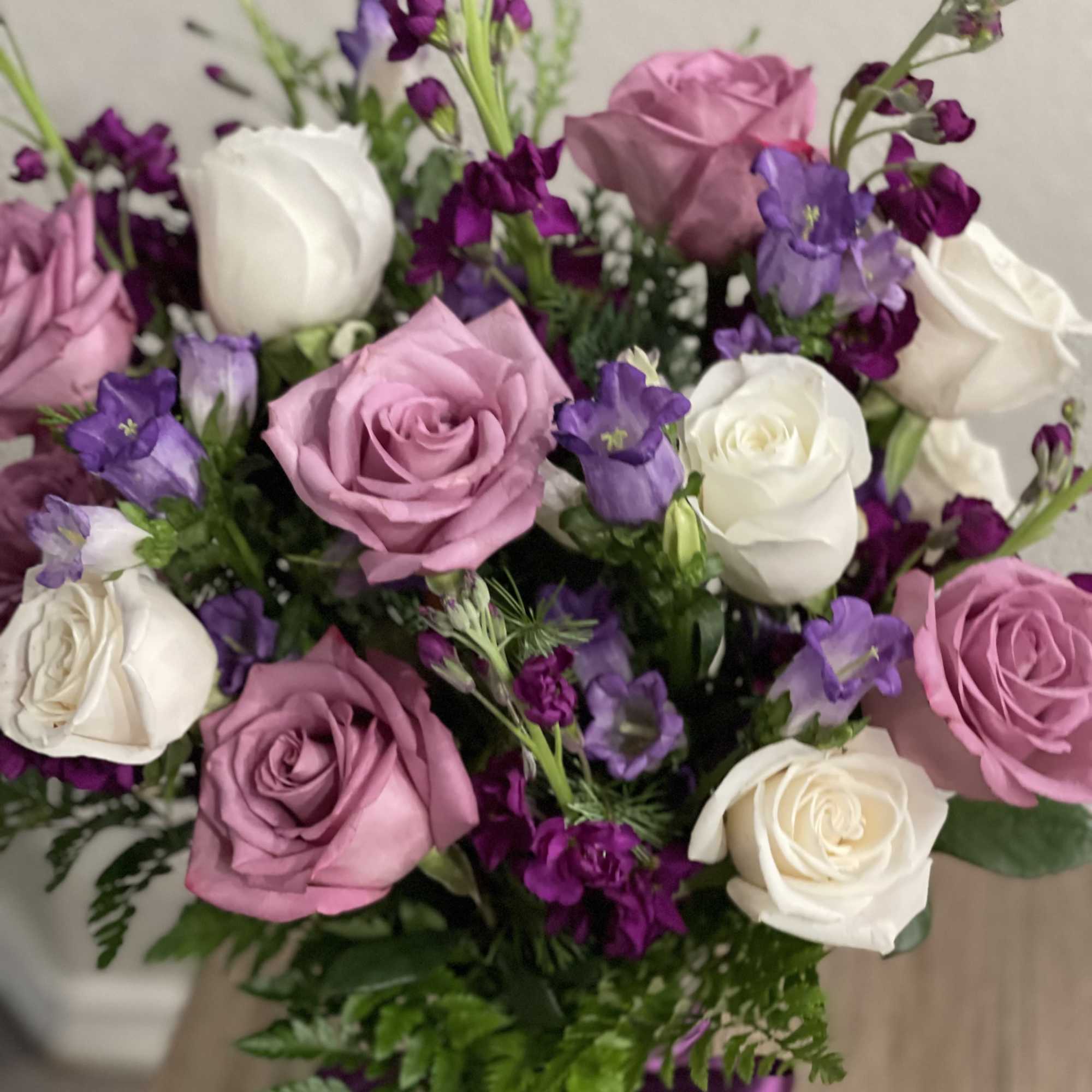 Bouquet of pink, white, and purple roses with small purple flowers