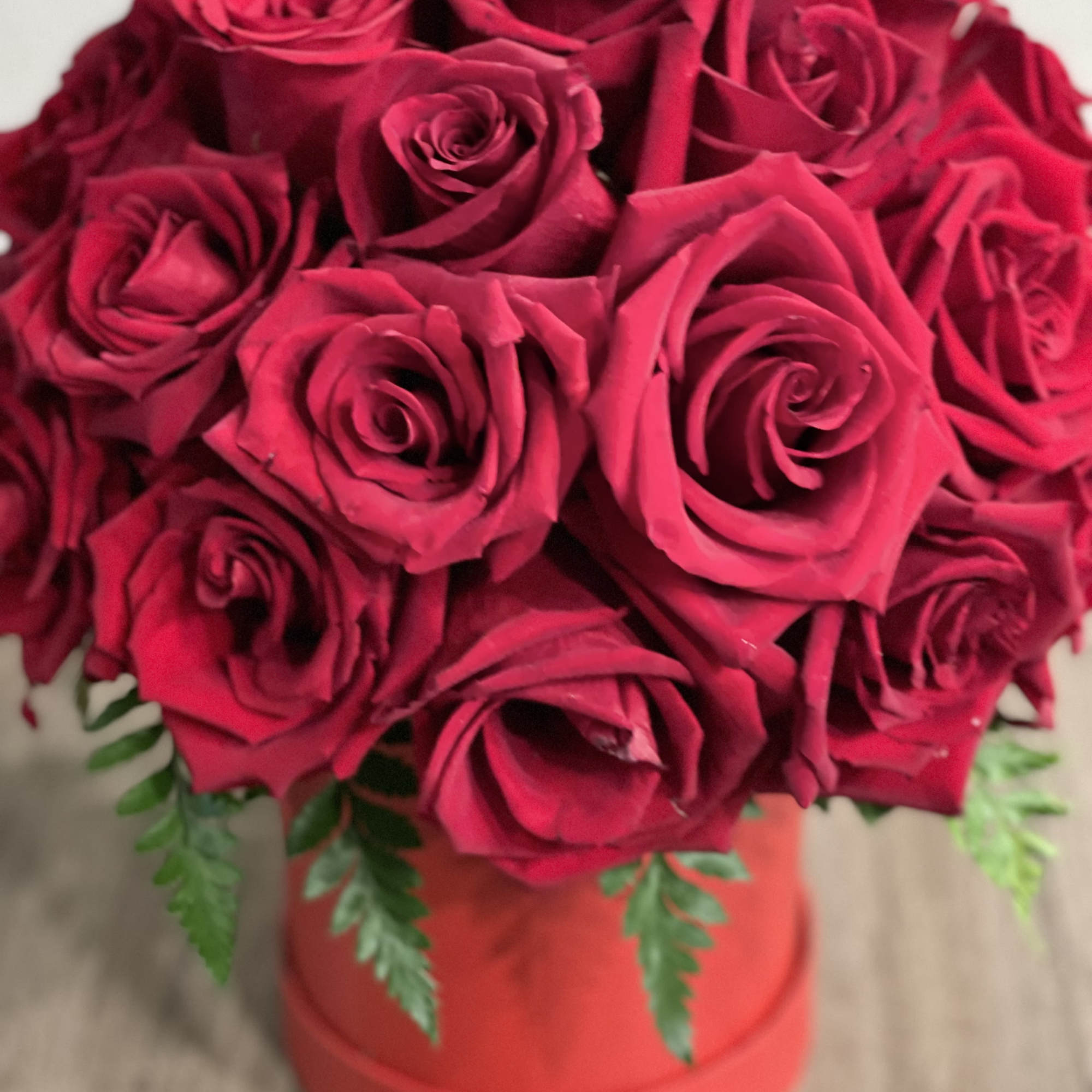 Bouquet of red roses in a red box with fern accents