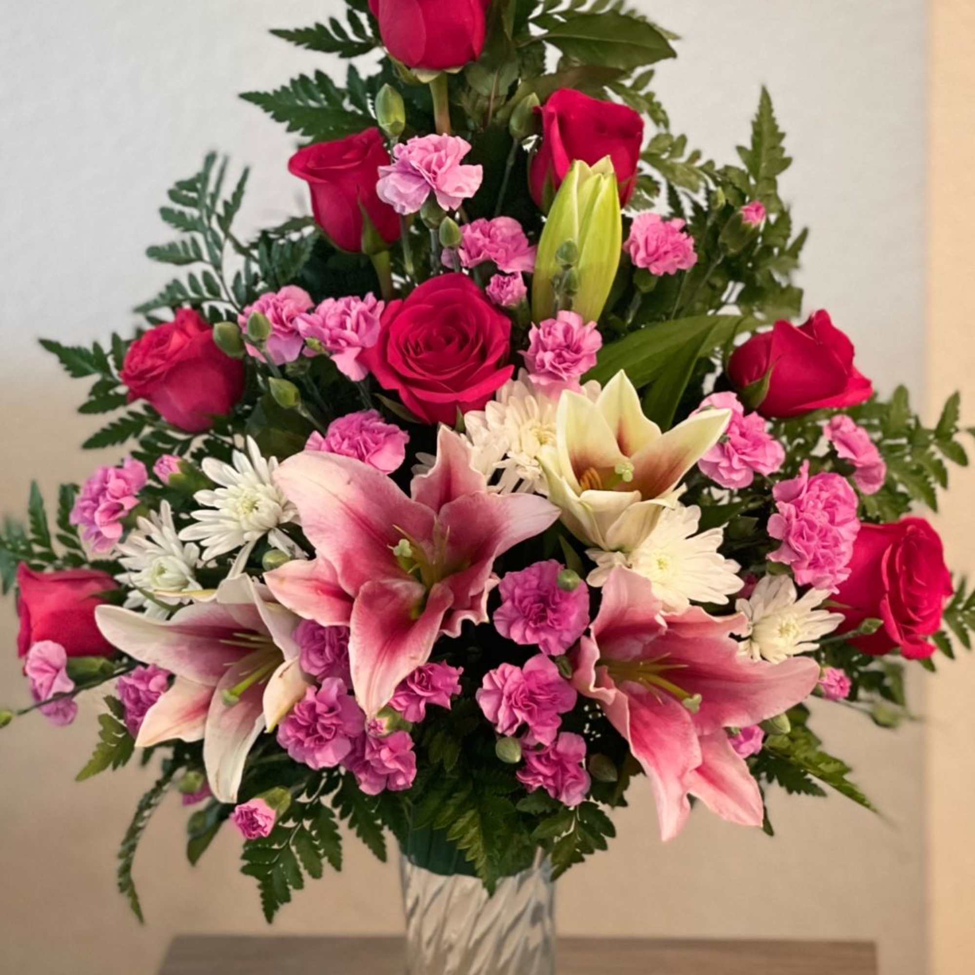 Pink roses and lilies arranged in a clear glass vase