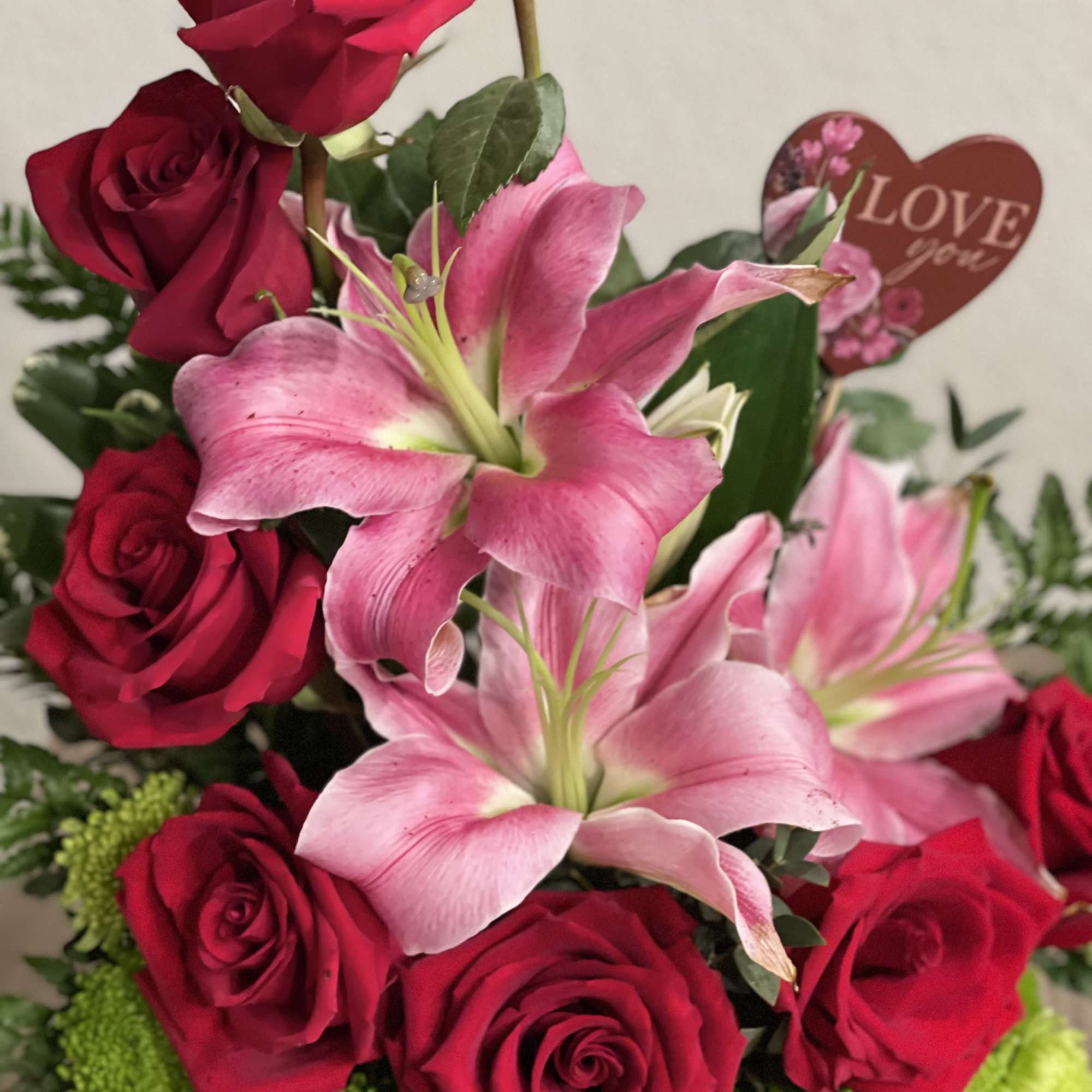 Red roses and pink lilies with a heart-shaped "Love you" pick