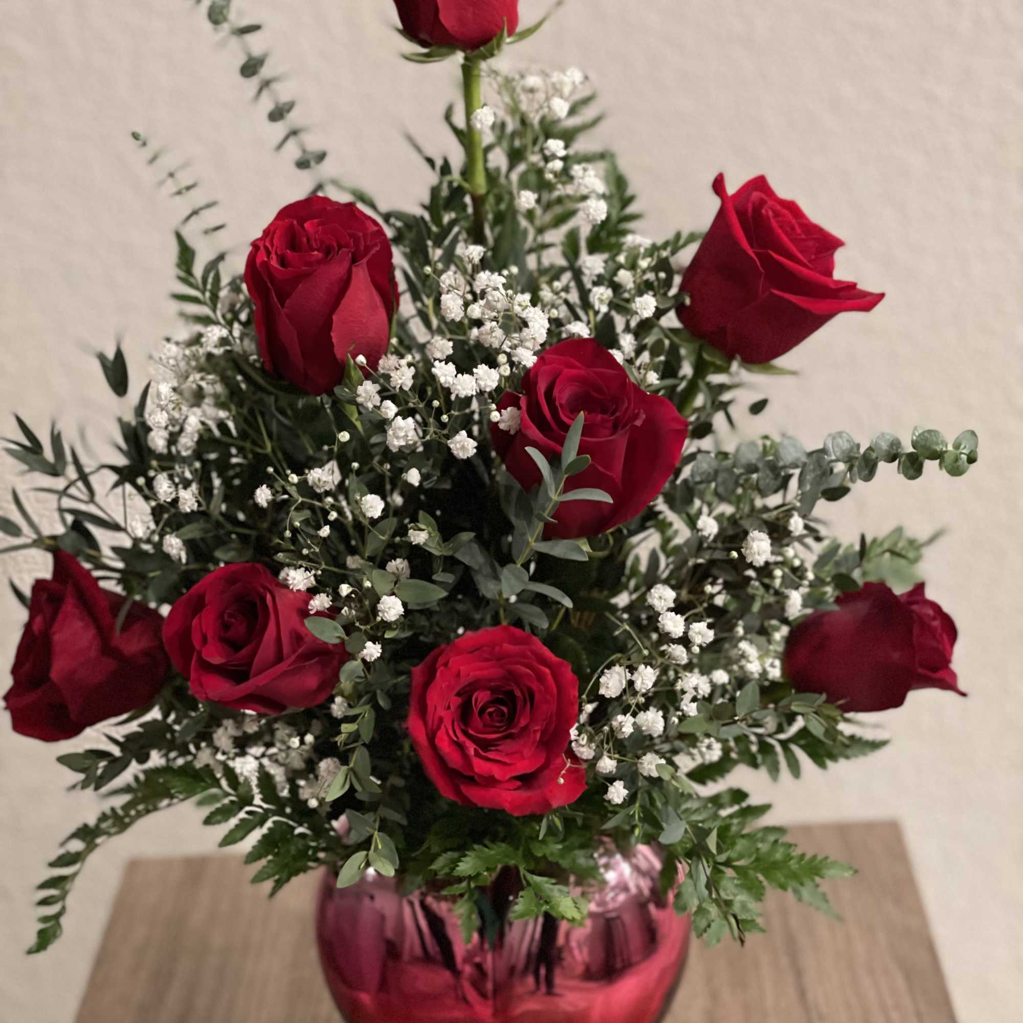 Red roses arranged in a pink glass vase with white filler flowers, photo 2 of 3