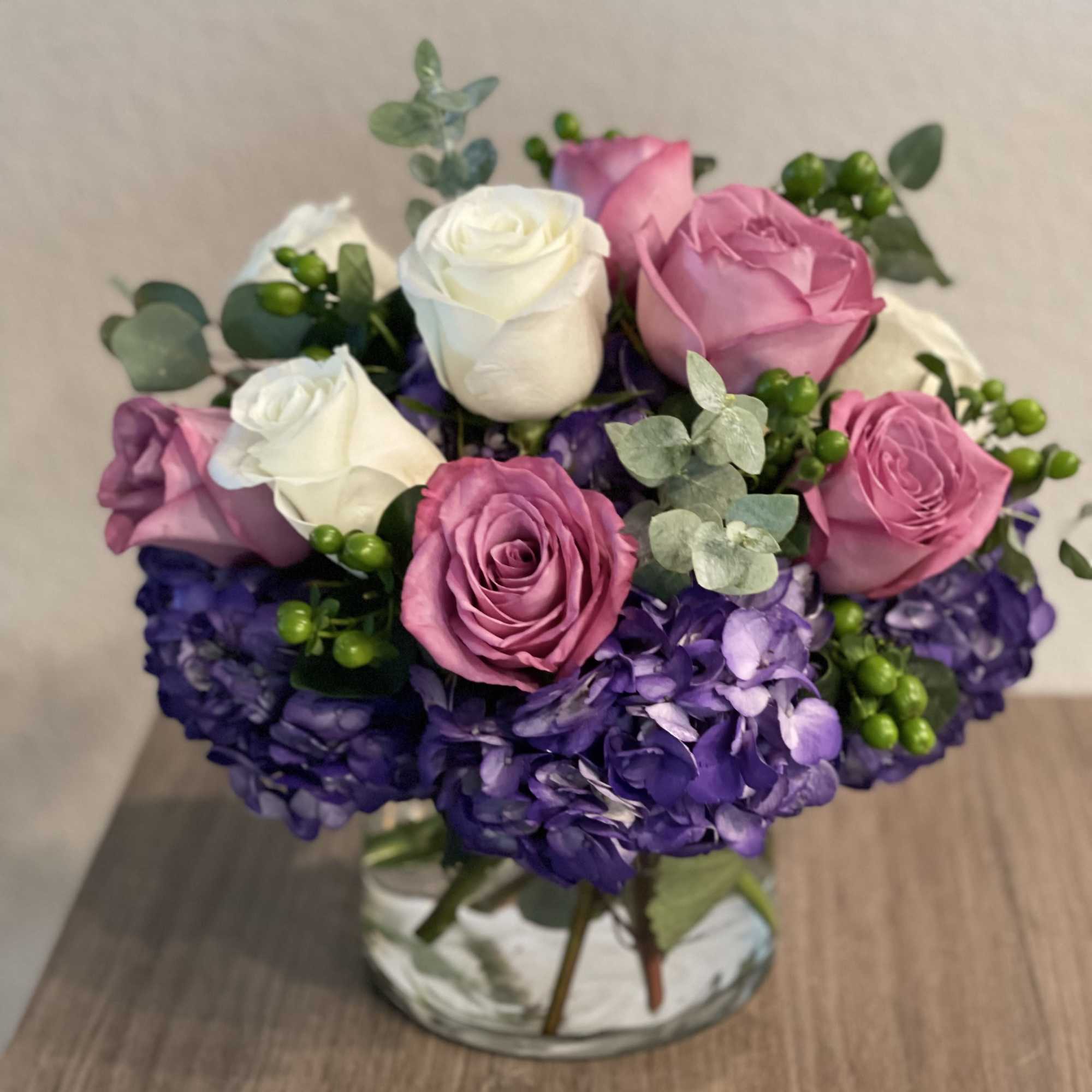Bouquet of pink and white roses with purple hydrangeas in a vase