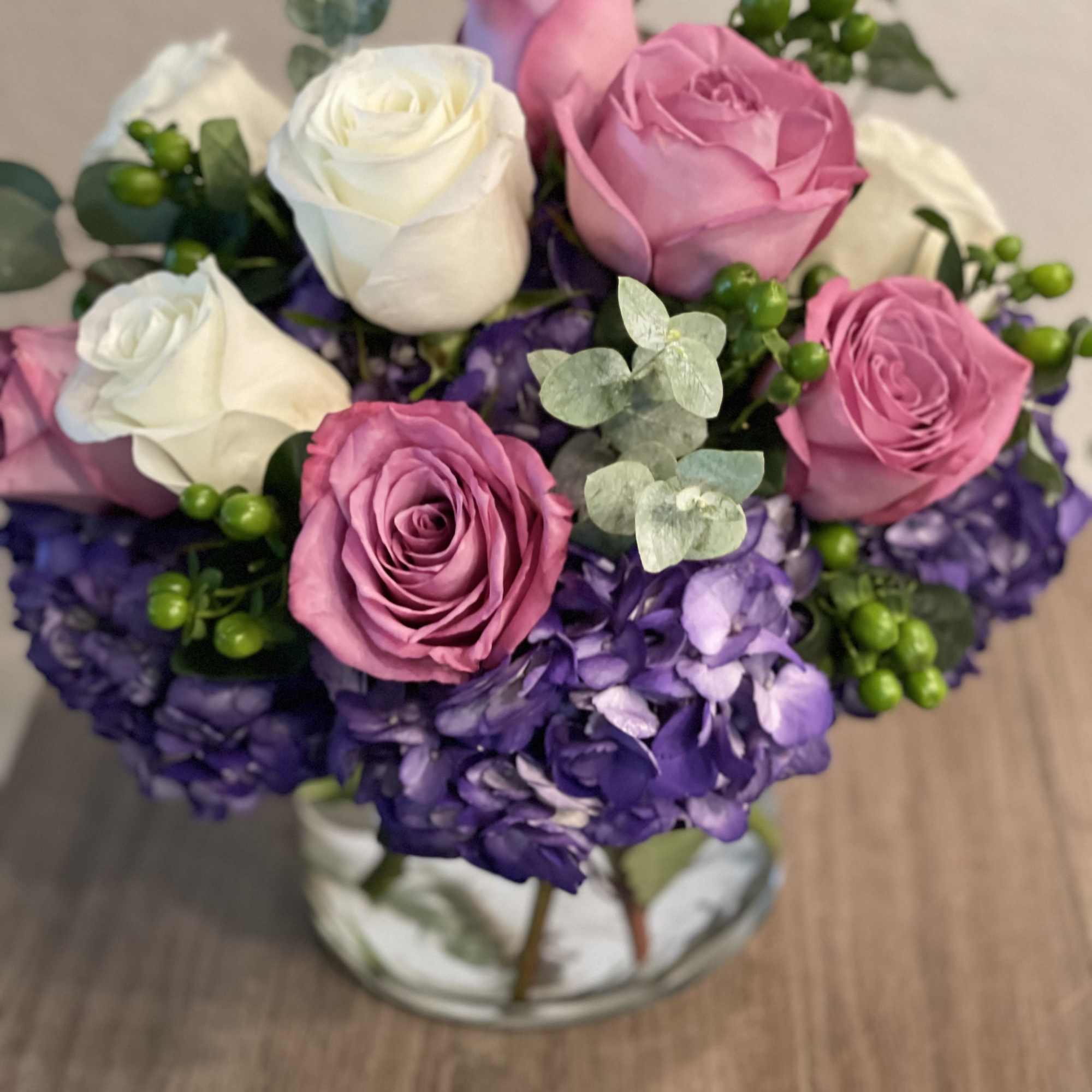 Pink and white roses with purple hydrangeas in a glass vase