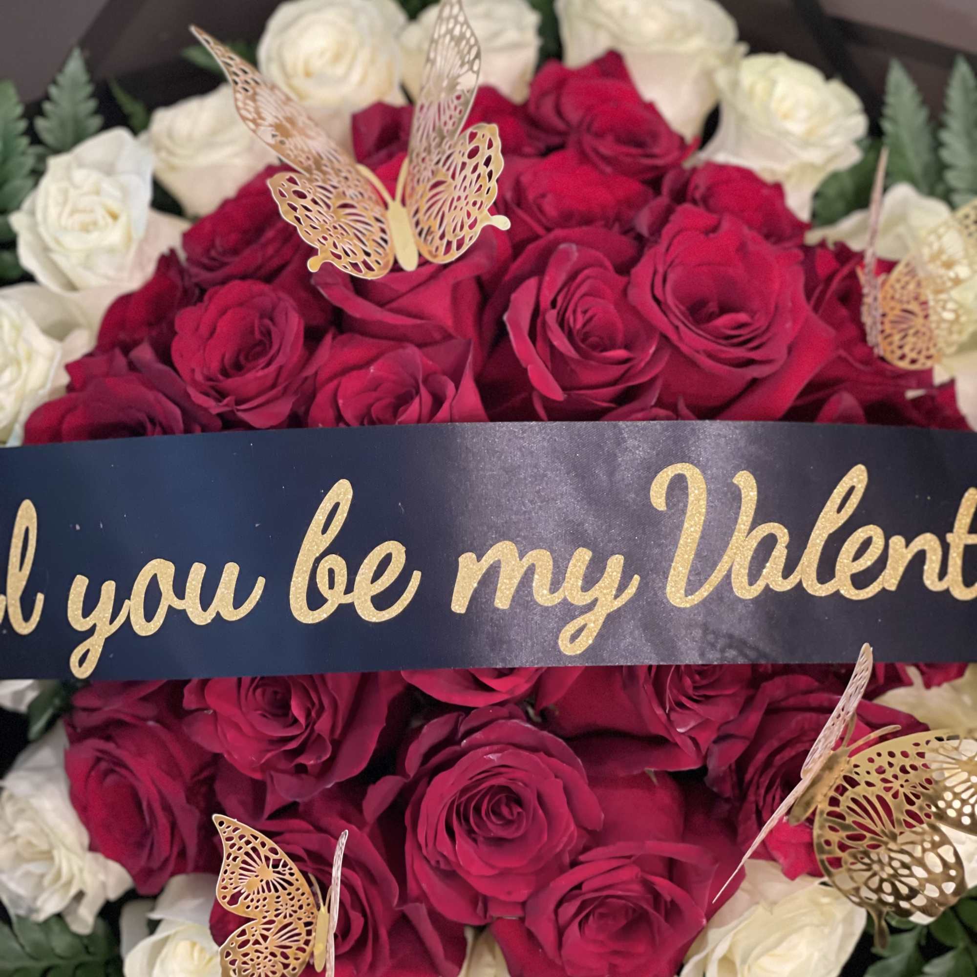 Bouquet of red and white roses with butterfly decorations and a Valentine ribbon