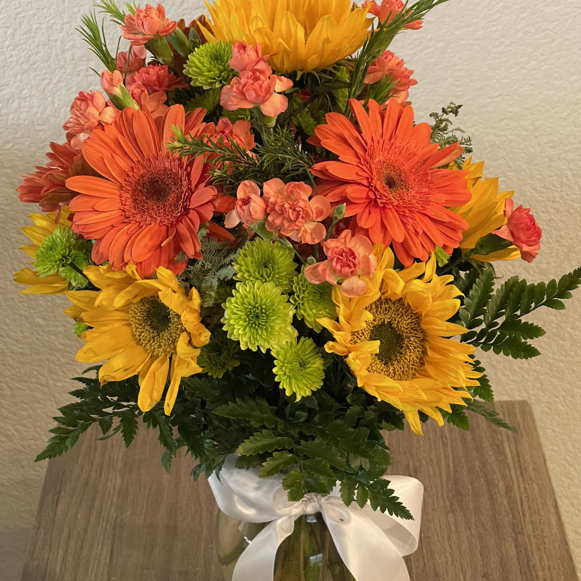 Elegant bouquet of long stem orange roses with assorted greenery all around