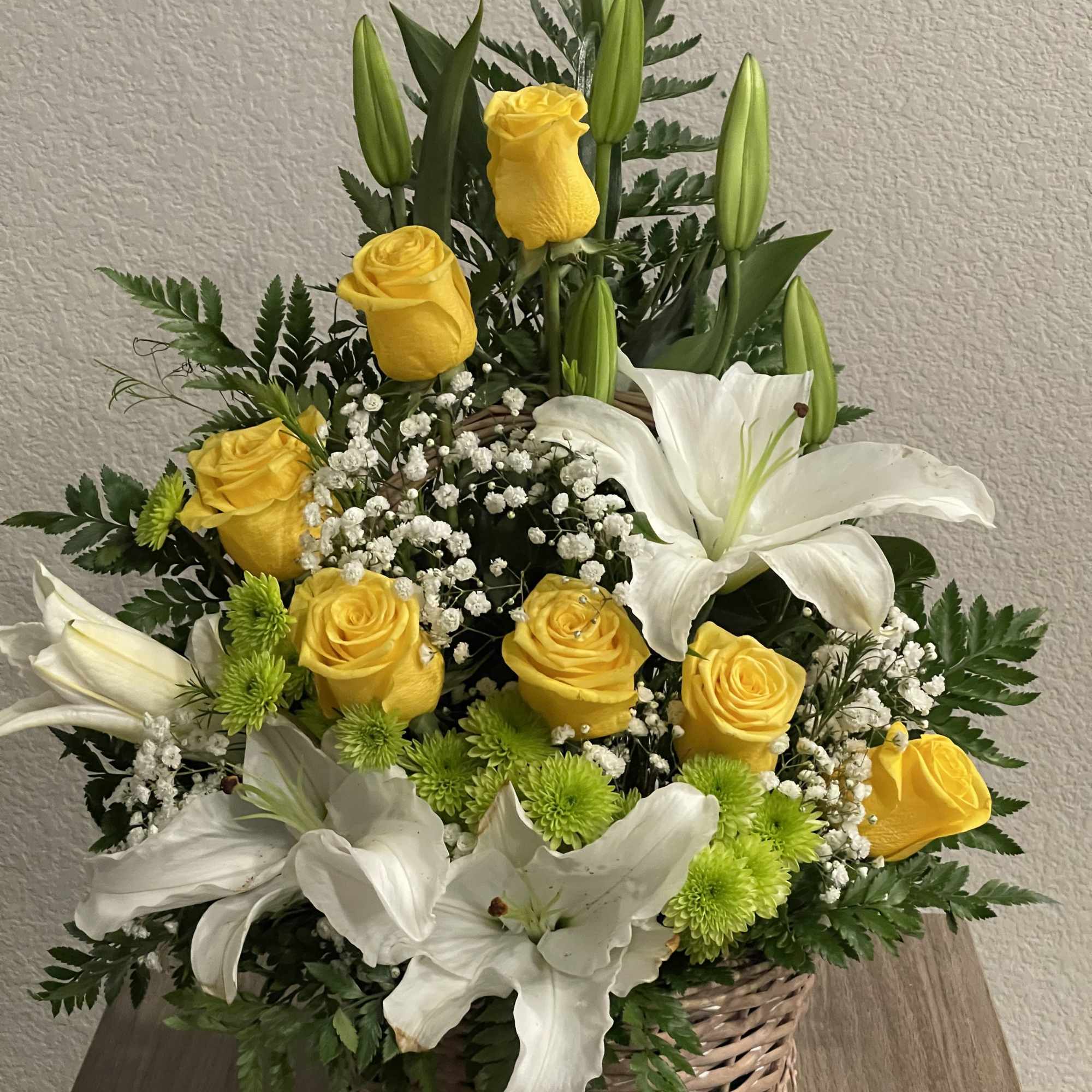 Sunlit yellow roses and large white lilies unite in a wicker basket