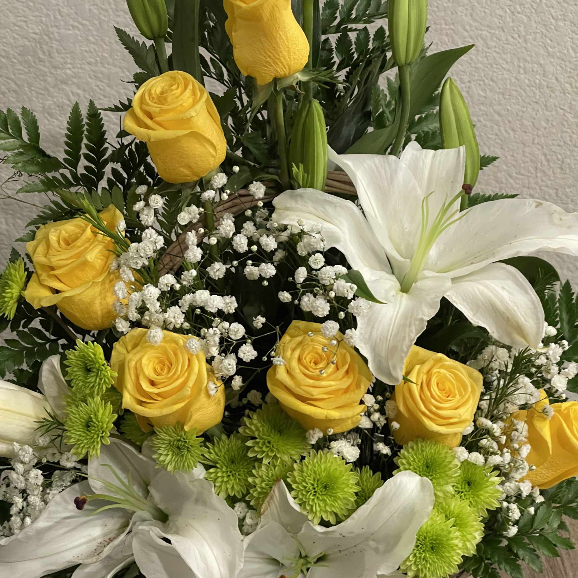 Sunlit yellow roses and large white lilies unite in a wicker basket, photo 2 of 2
