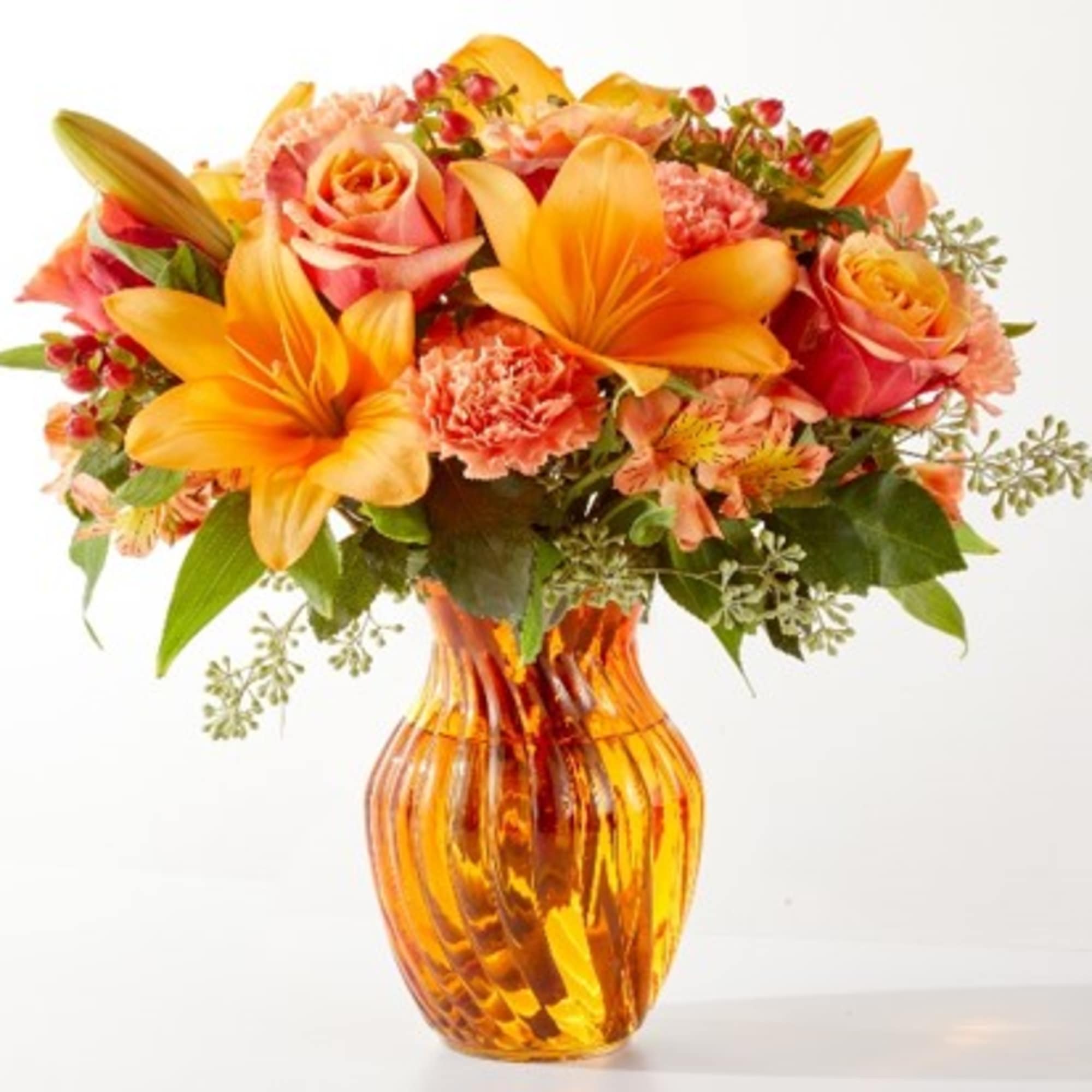 Orange and pink floral bouquet in an amber glass vase