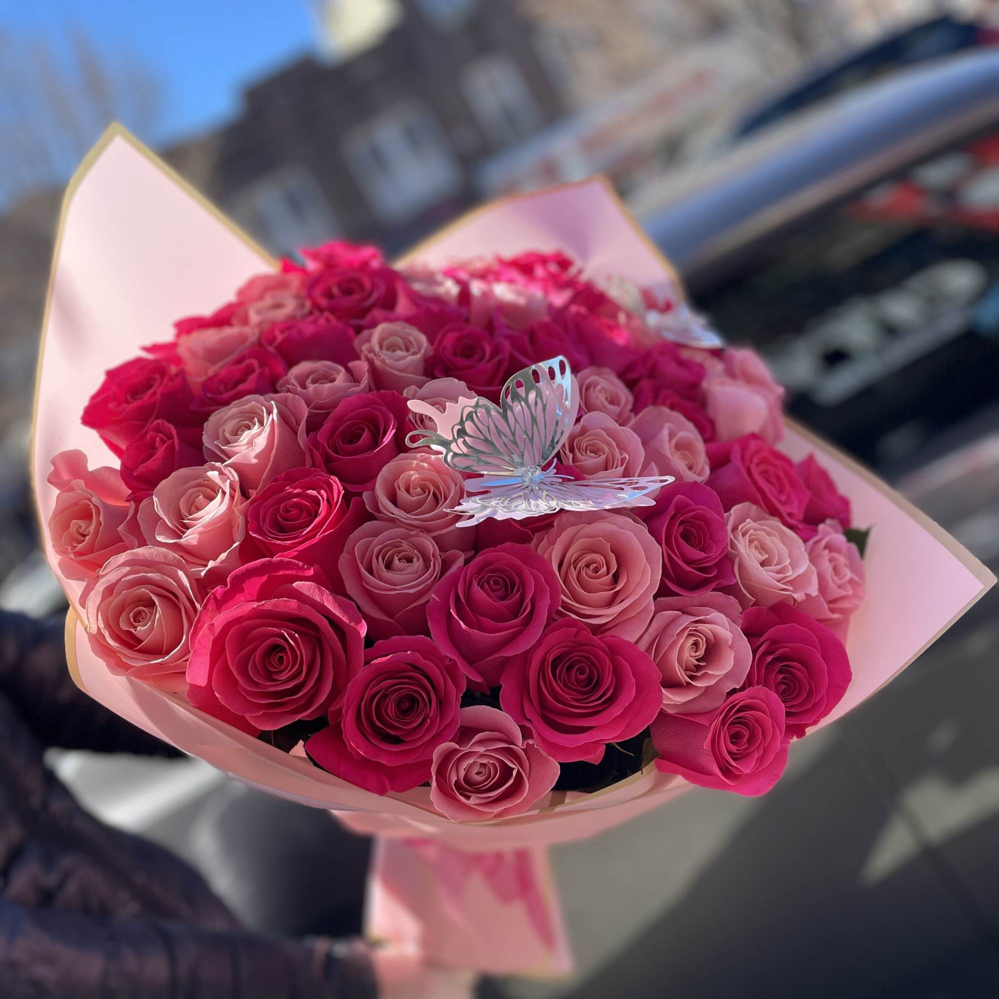 Bouquet of pink and hot pink roses with a butterfly pick