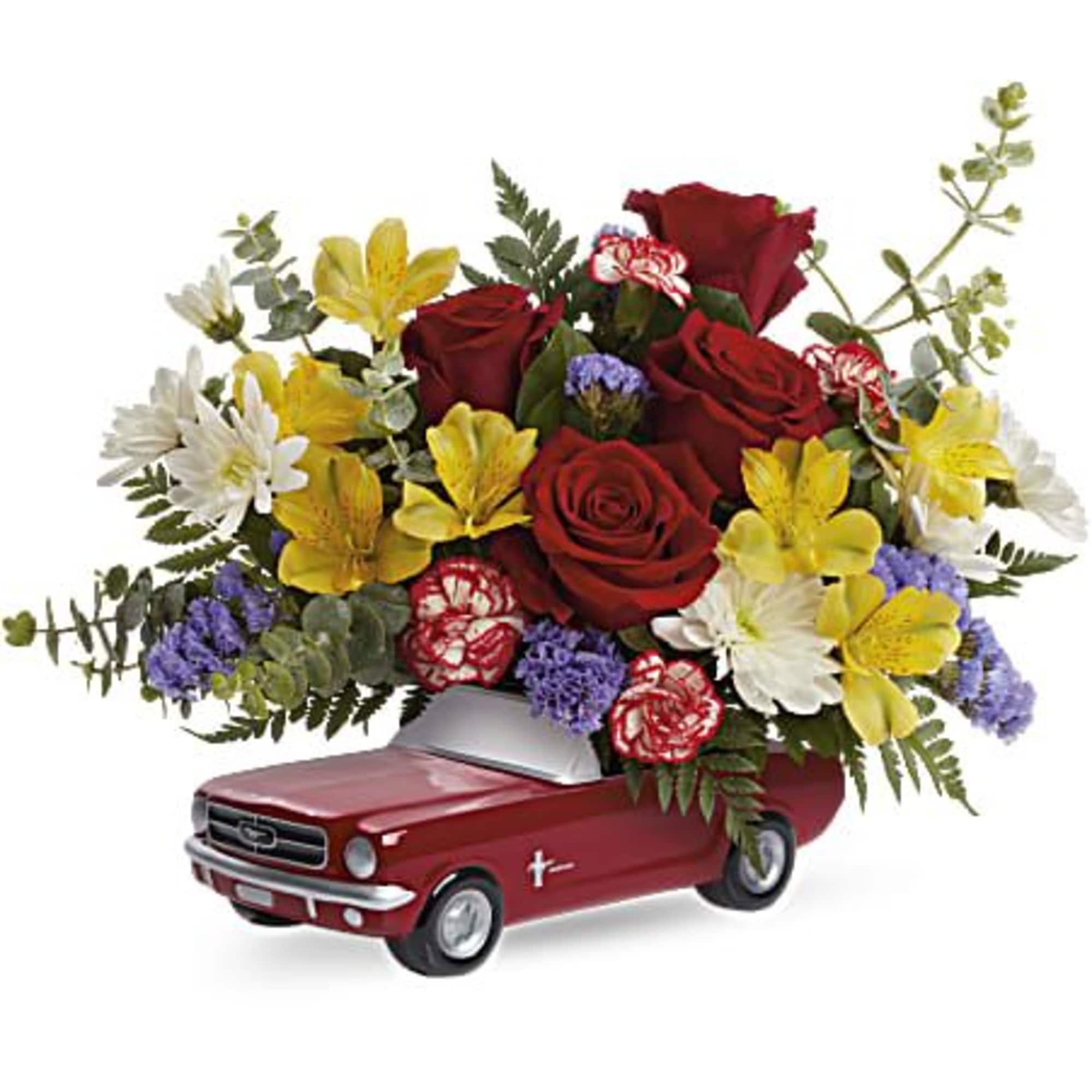 Red roses and mixed flowers arranged in a miniature car planter