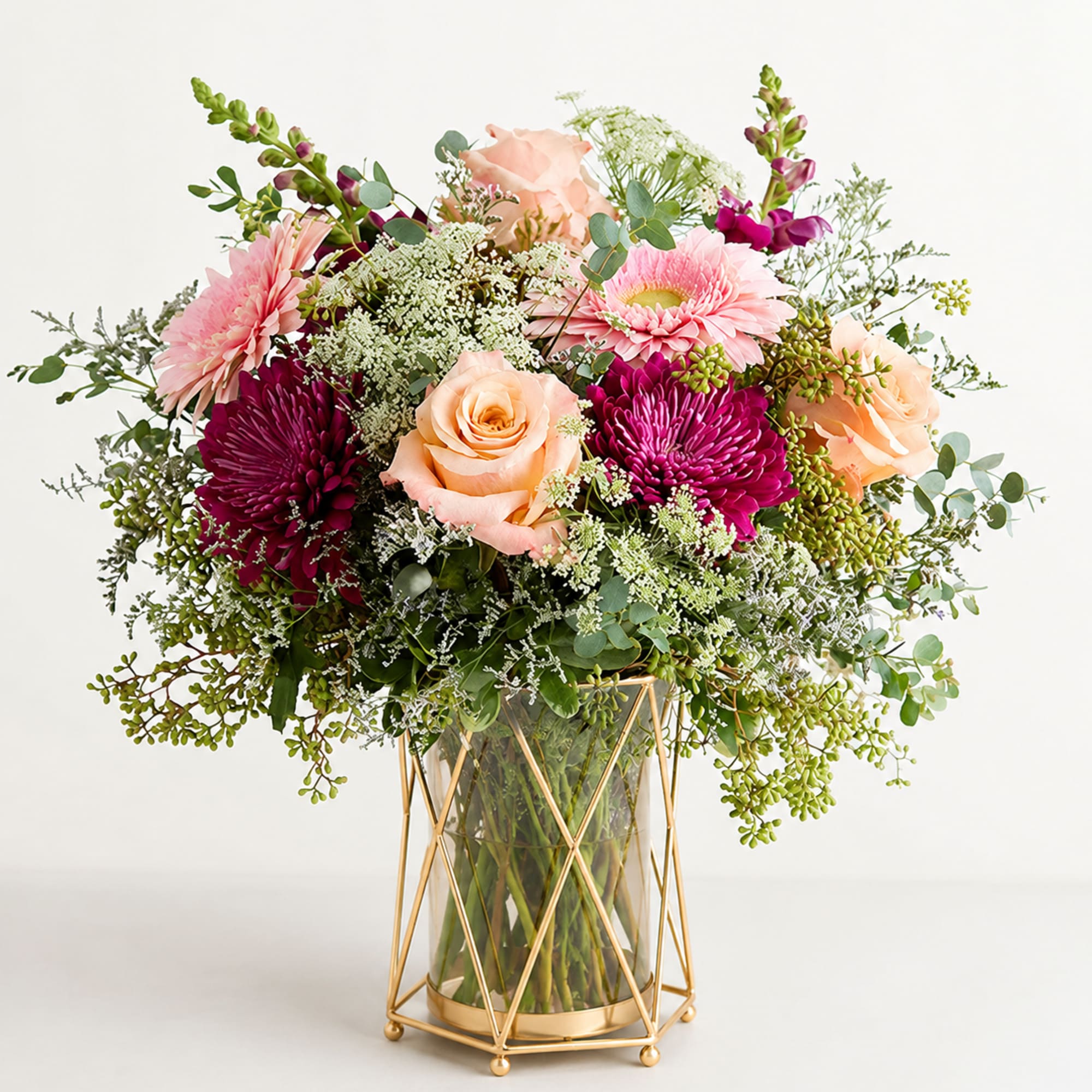 Pink and peach flowers in a glass vase with a gold stand