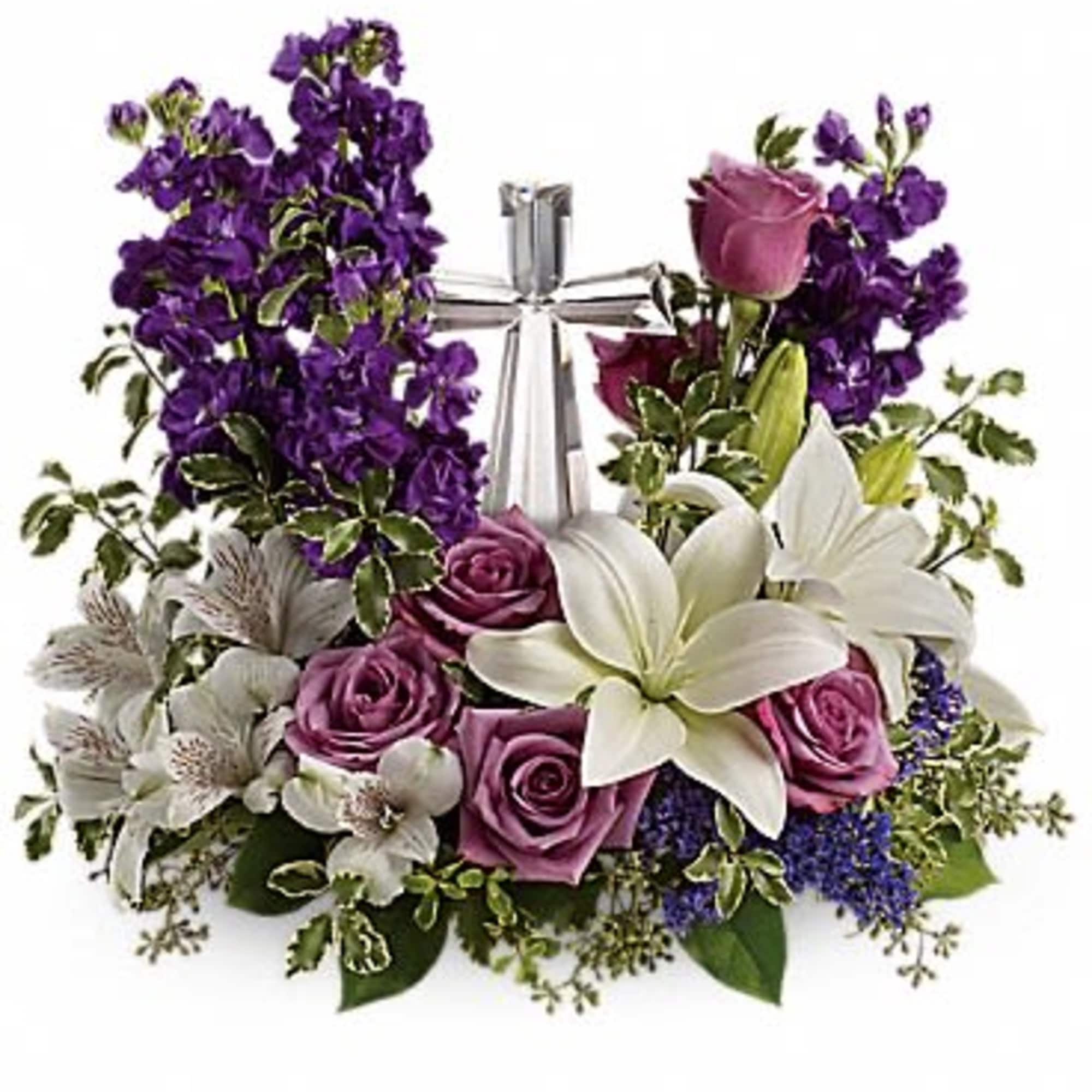 Purple and white floral arrangement with roses and lilies around a silver cross