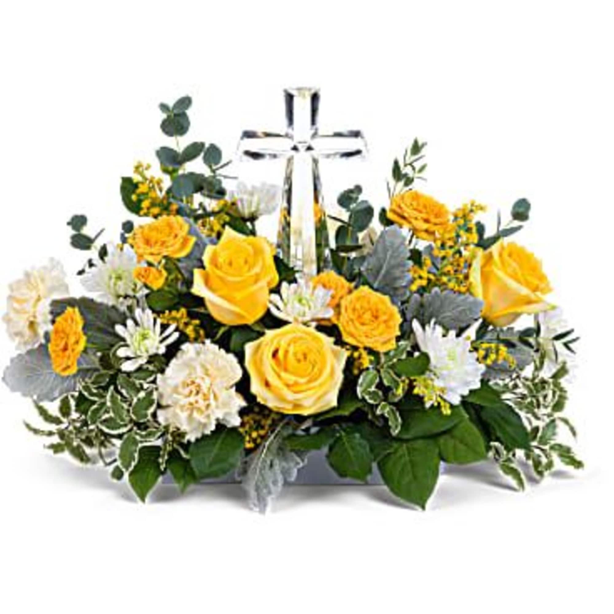 Yellow roses and white flowers arranged around a glass cross