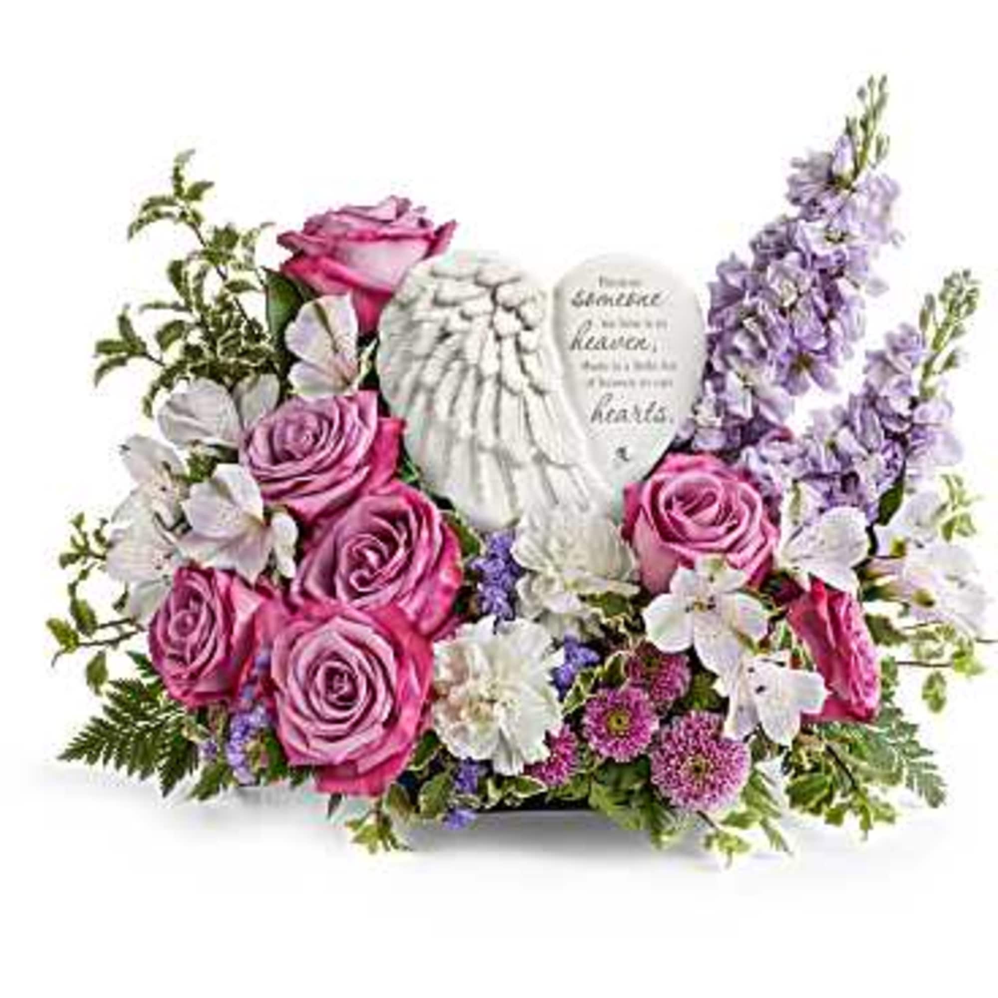 Pink roses and white flowers arranged around a memorial heart plaque