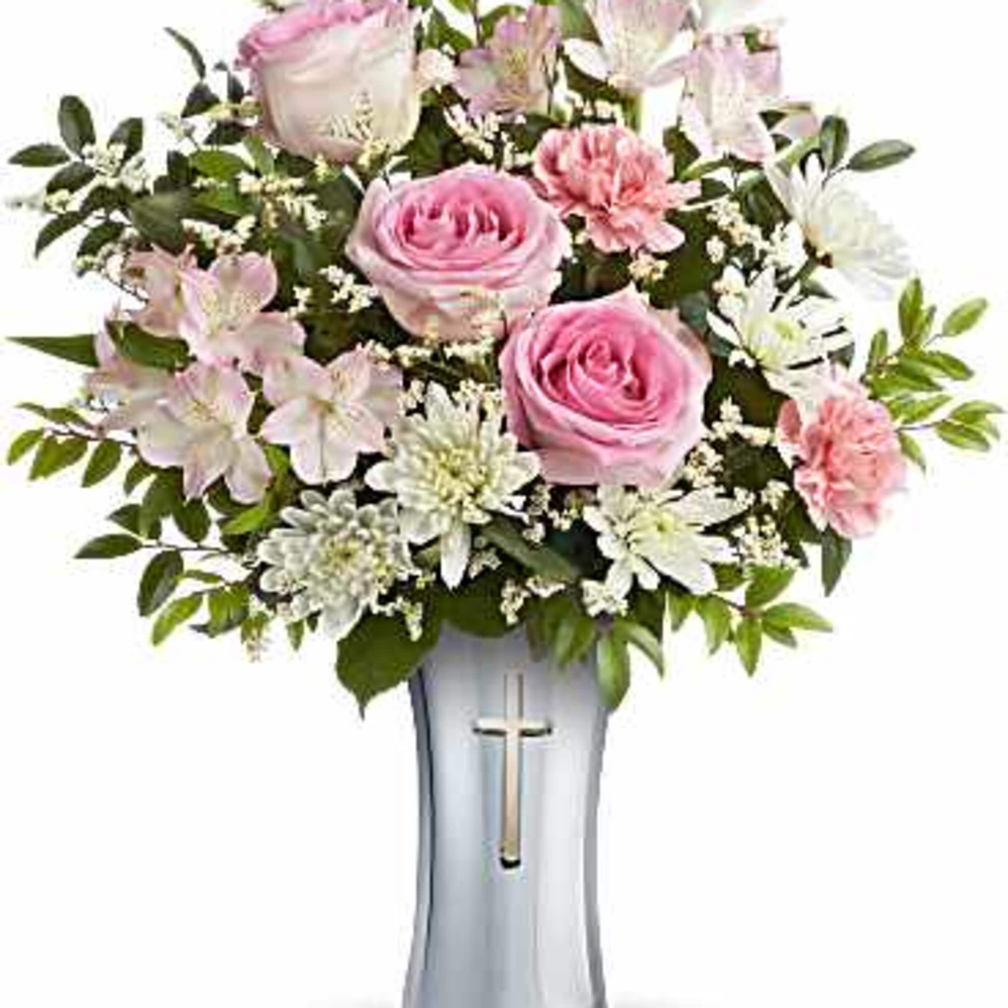 Pink roses and white flowers arranged in a silver vase with a cross