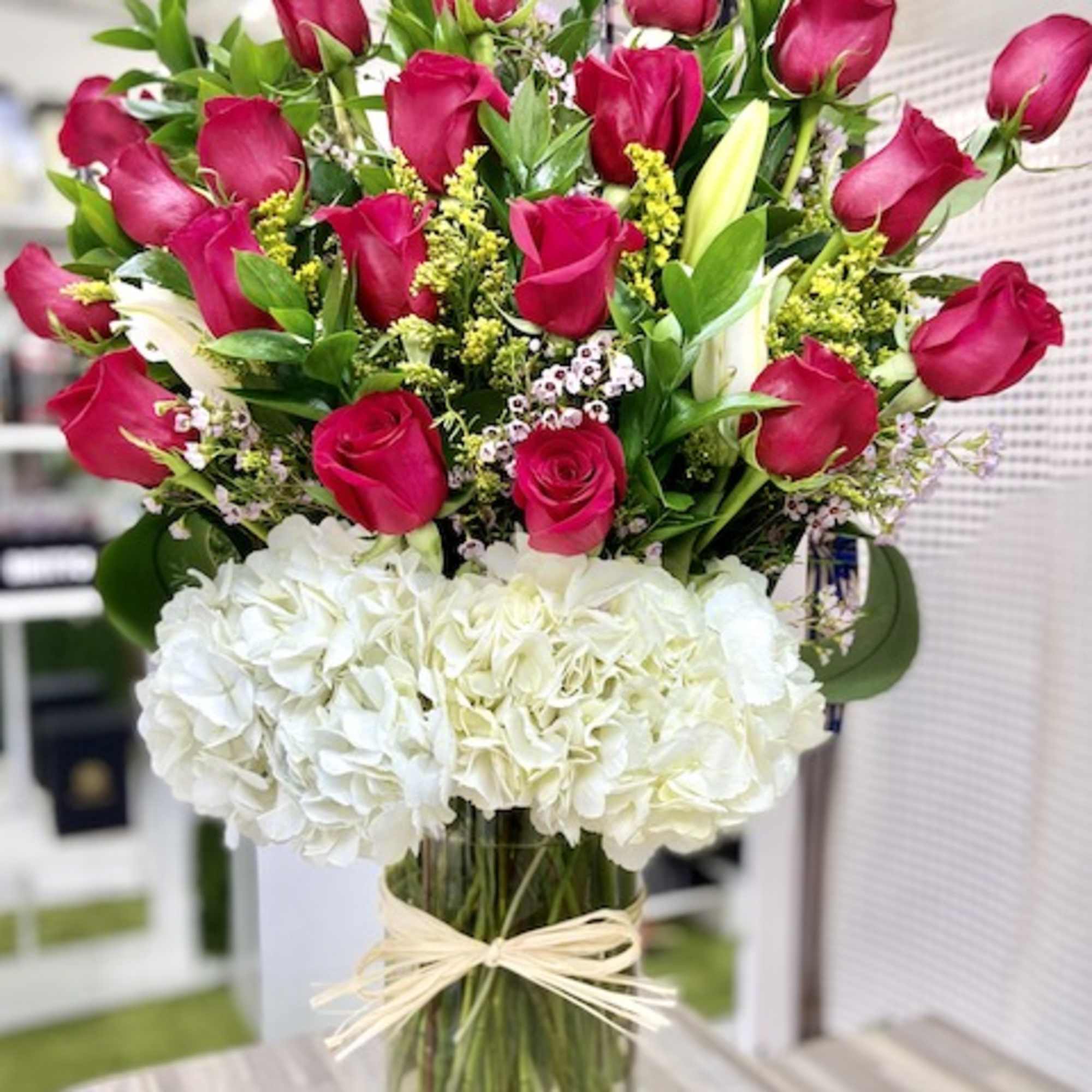 Tall arrangement of hot pink roses and white hydrangeas in a clear cylinder vase