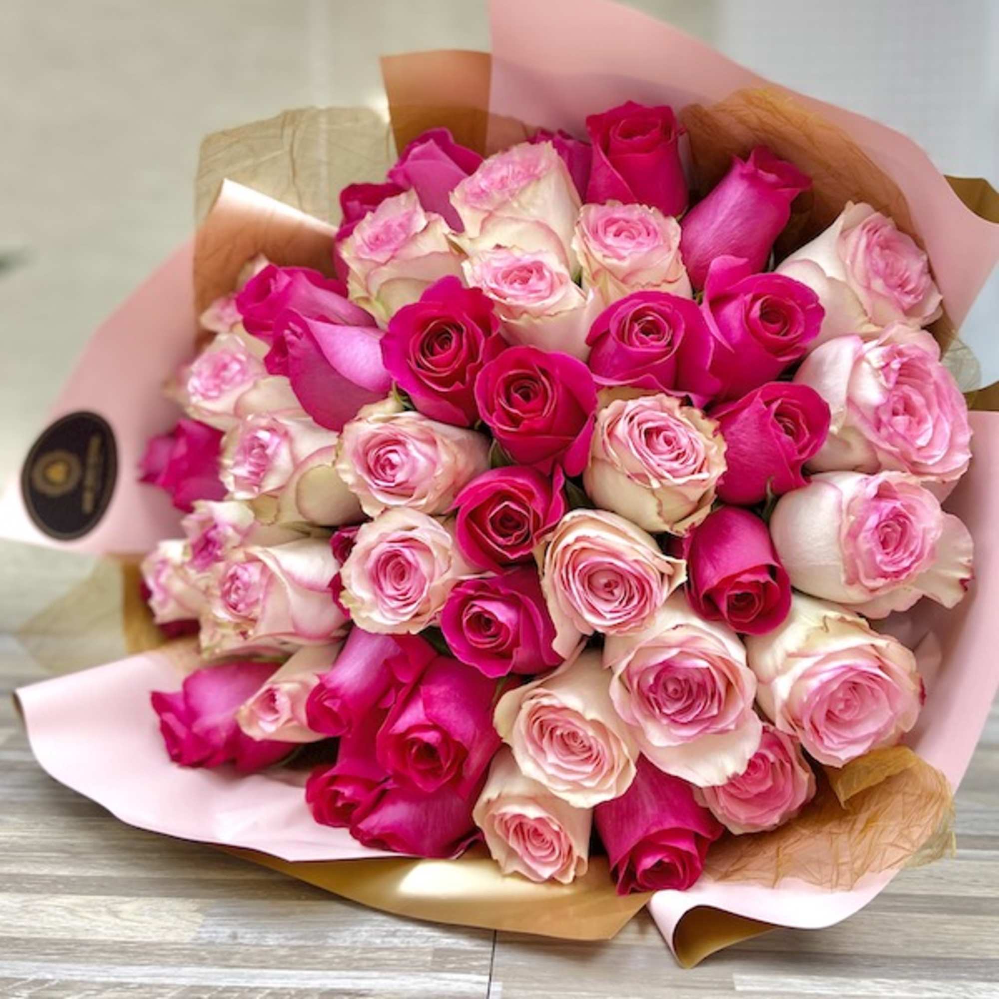 Large bouquet of hot pink and pale pink roses wrapped in pink and kraft paper