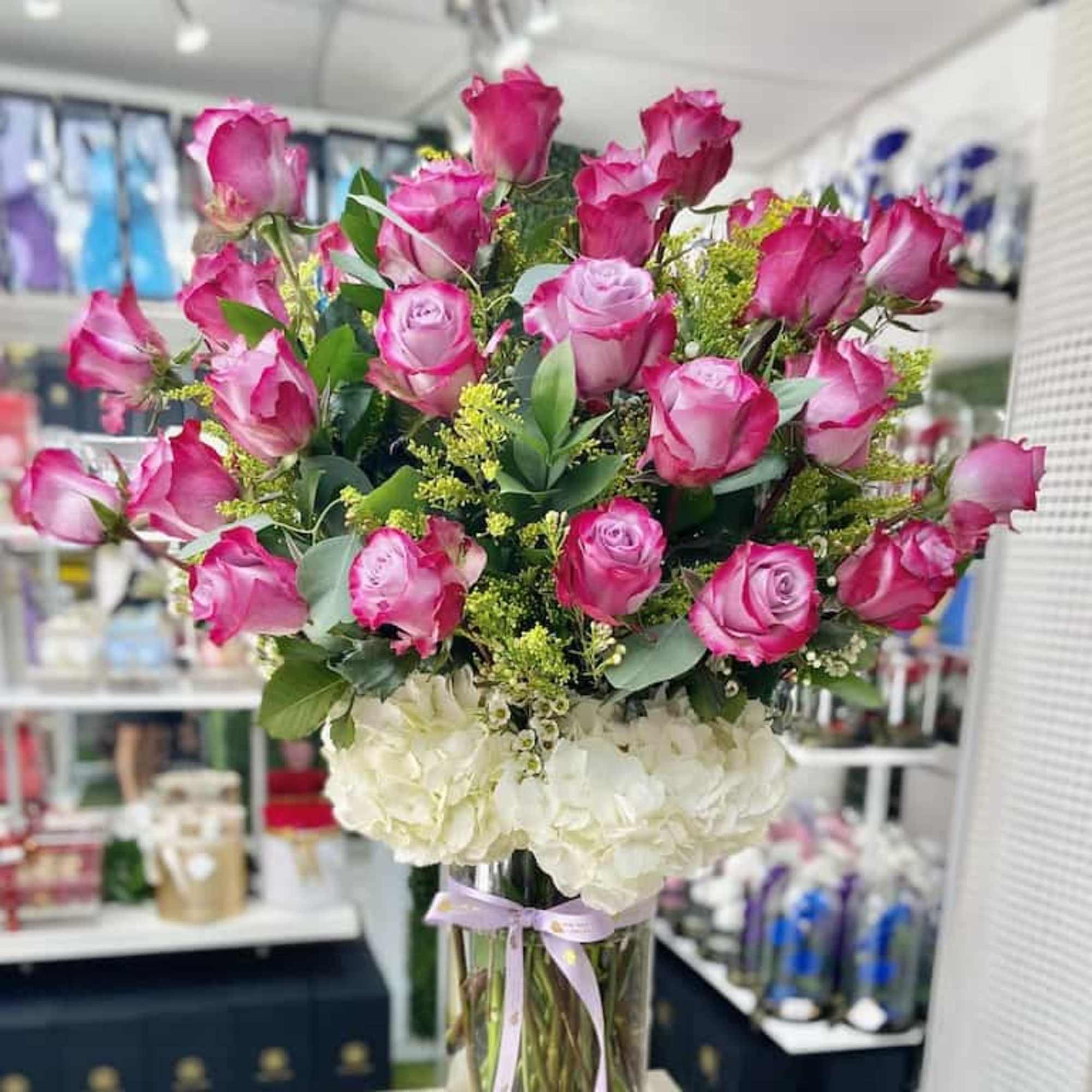 Tall vase arrangement of hot pink roses and white hydrangeas tied with a ribbon