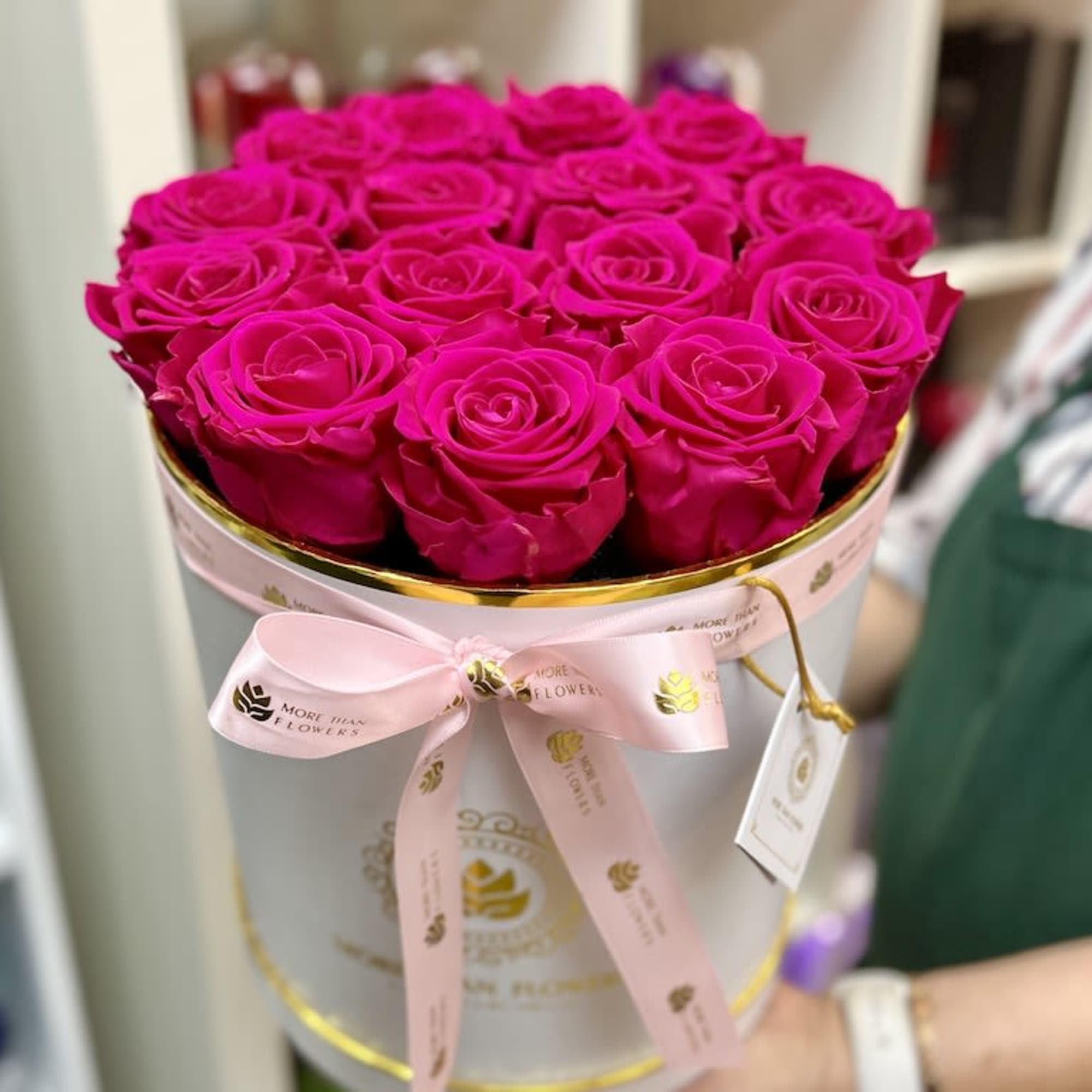 Round white hatbox filled with tightly packed hot pink roses and tied with a pink ribbon