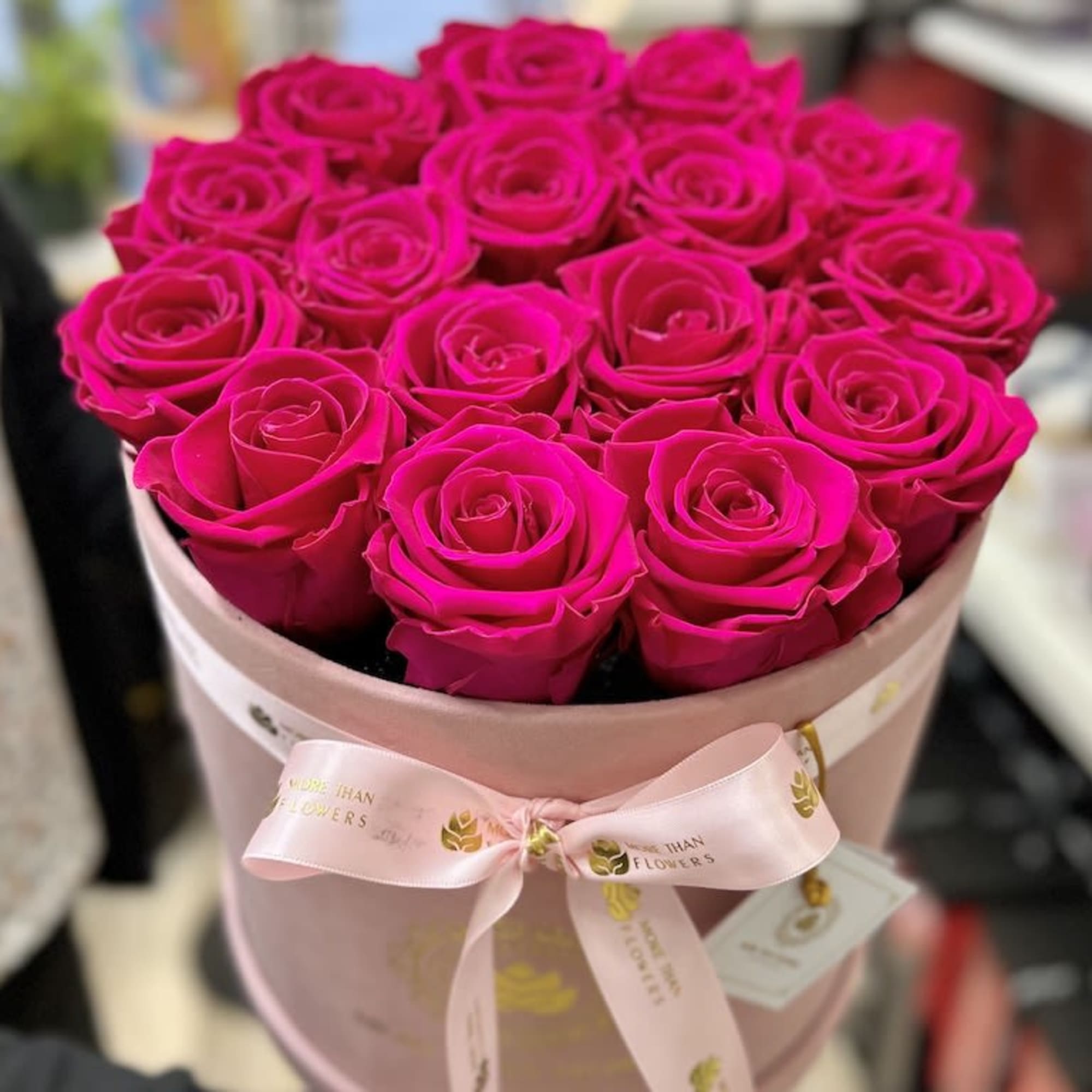 Round hatbox of bright pink roses with a pink ribbon bow
