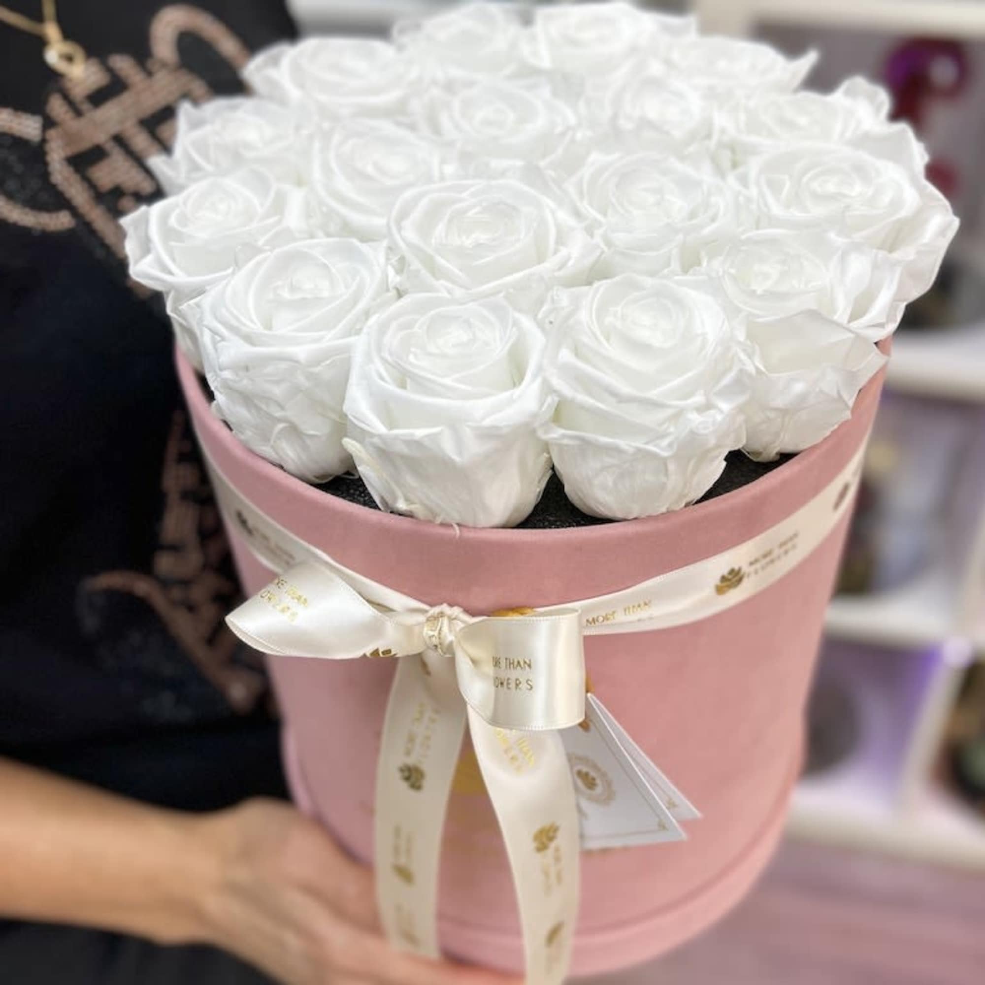 Round pink hatbox packed with white roses and tied with an ivory ribbon.