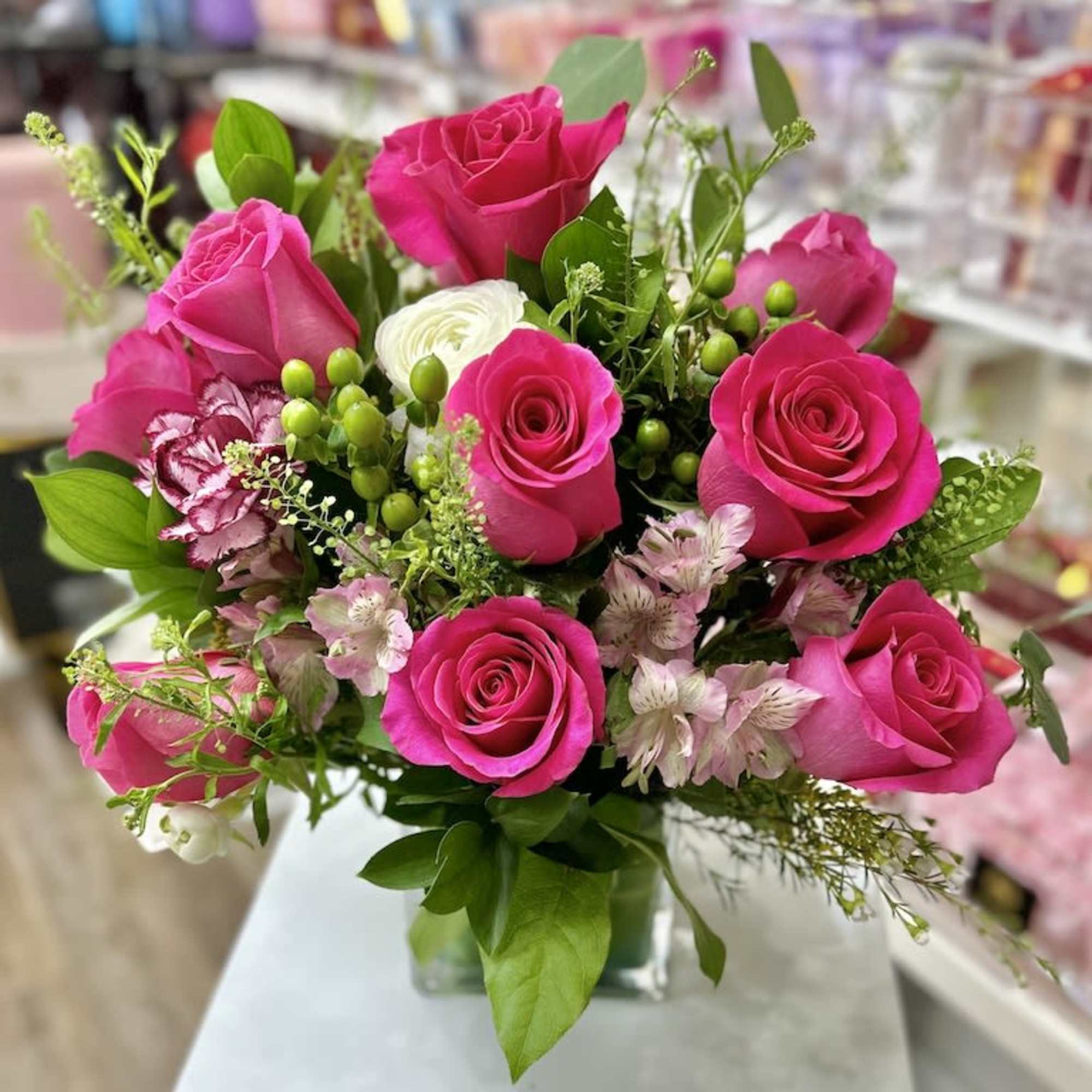 Bright pink rose and light pink alstroemeria arrangement with white accents in a square glass vase