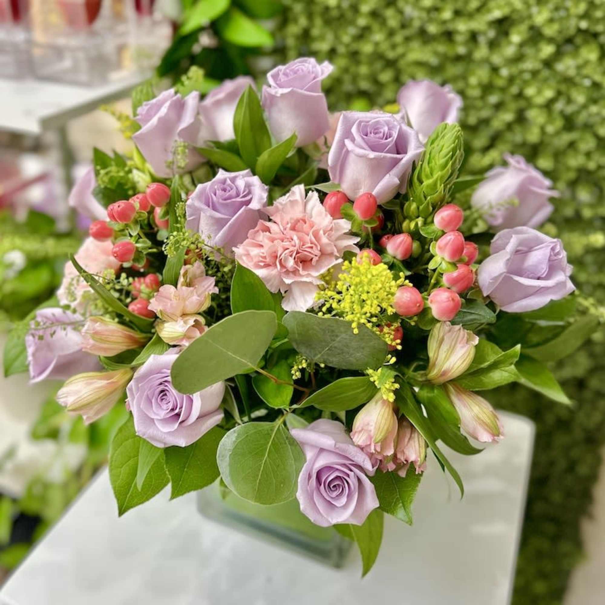 Lavender rose and pink mixed flower arrangement in a clear glass cube vase