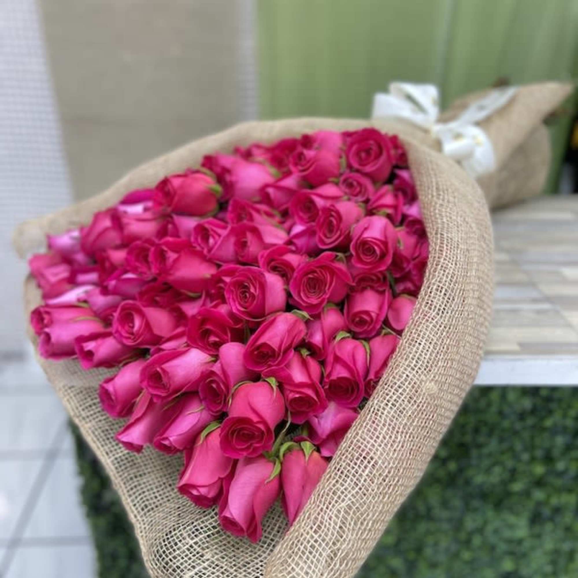 Large bundle of bright pink roses wrapped in natural burlap fabric