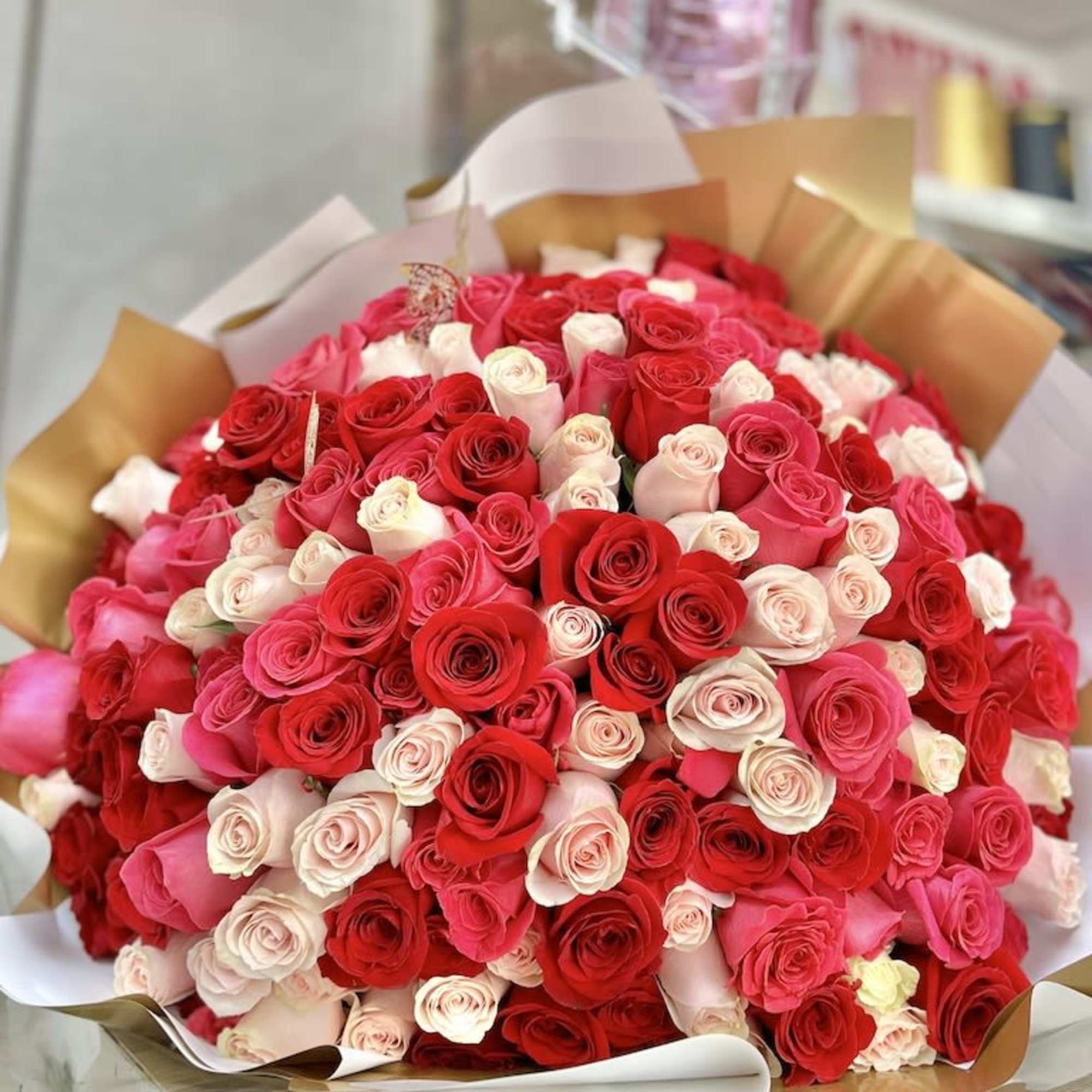 Extra-large bouquet of red, pink, and cream roses wrapped in white and gold paper