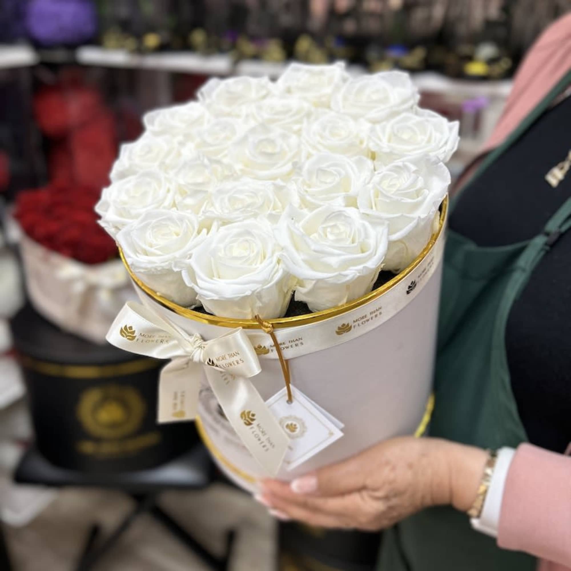 Round white box filled with tightly packed white roses held in both hands