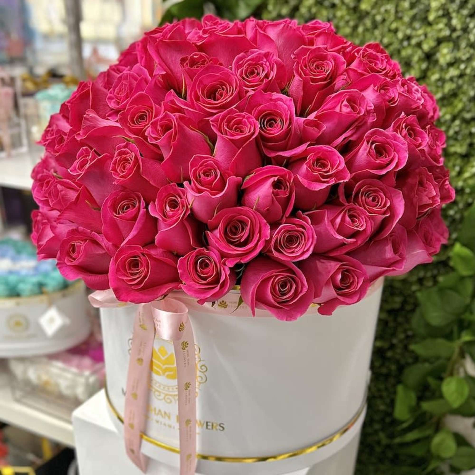 Large arrangement of hot pink roses in a white hat box with a pink ribbon