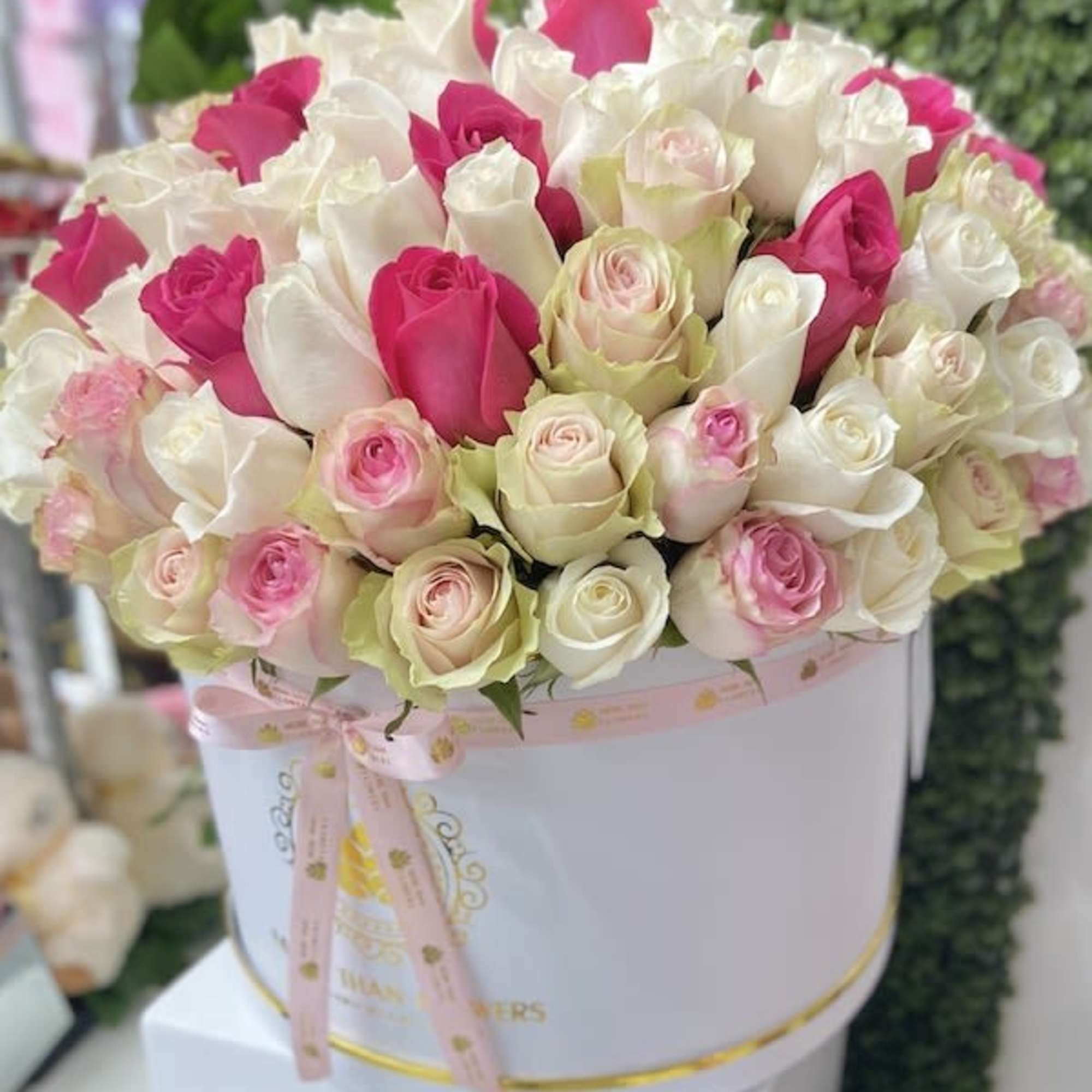 Round hatbox of white, pink, and blush roses tied with a pink ribbon