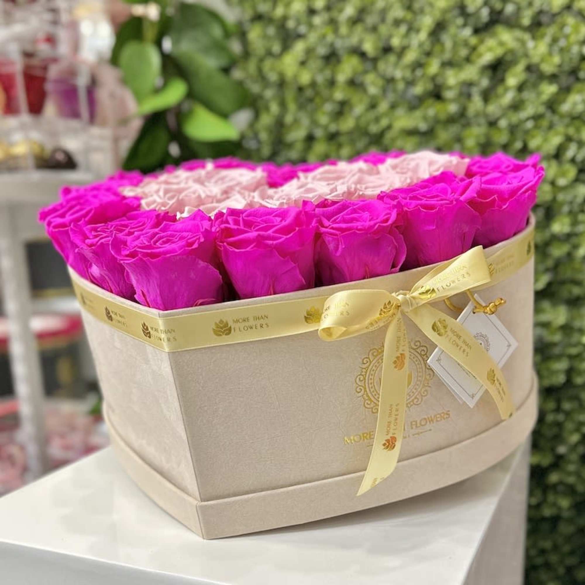 Cream box filled with bright pink and pale pink roses, tied with a yellow ribbon