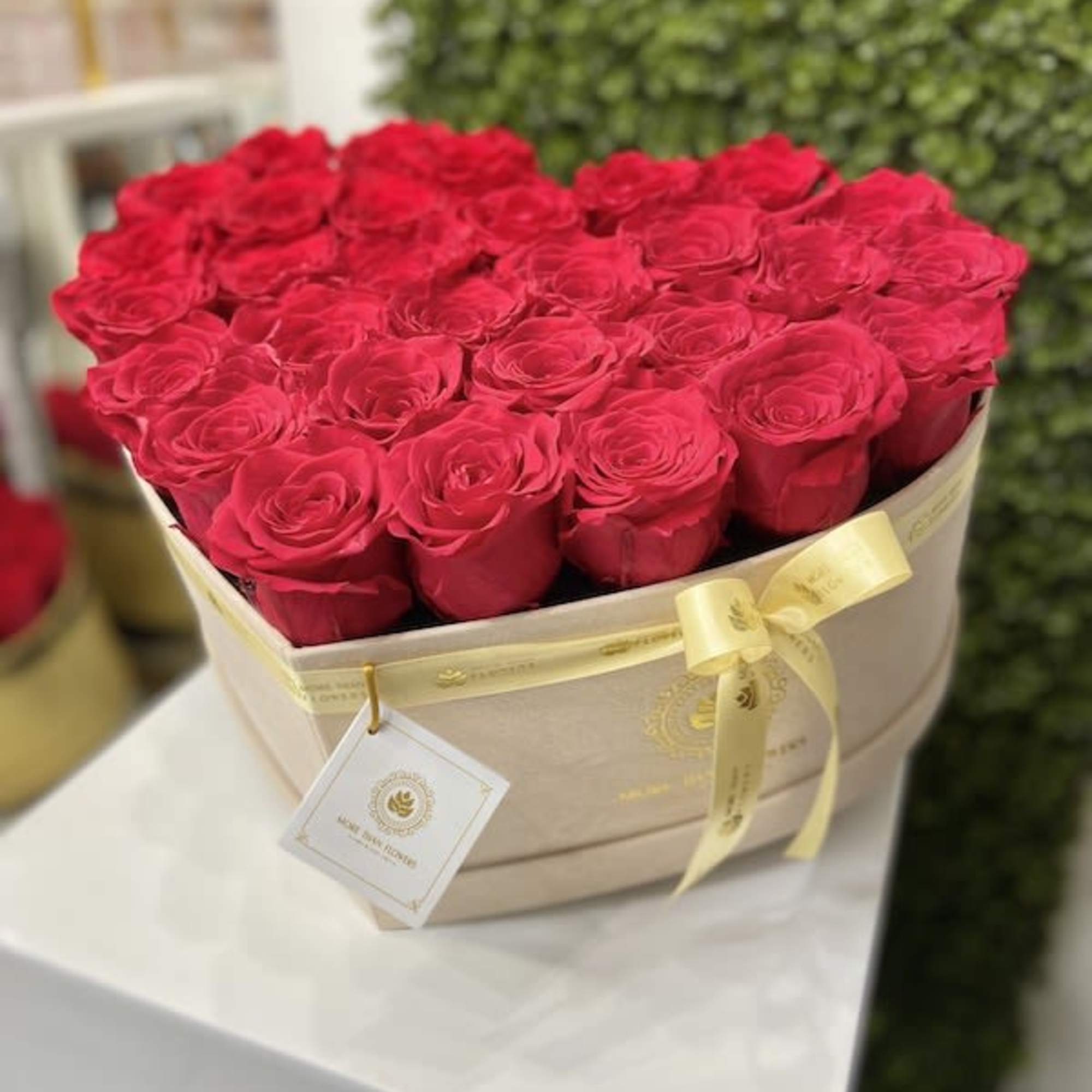 Heart-shaped beige box filled with red roses and tied with a yellow ribbon
