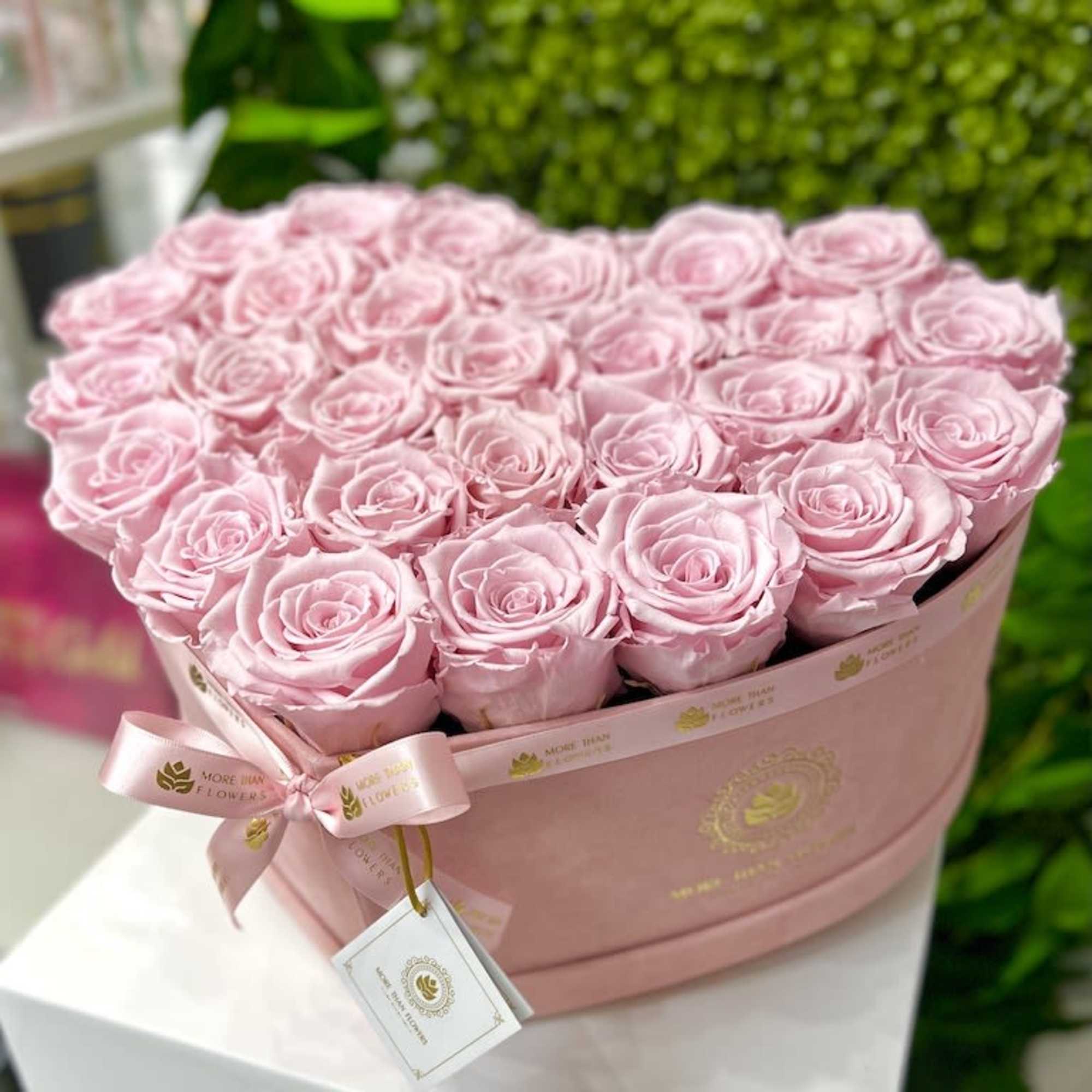 Heart-shaped pink box filled with tightly packed light pink roses